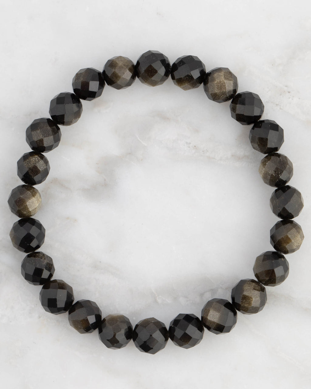 Pulsera de Obsidiana Dorada facetada, pieza completa en círculo sobre mármol claro
