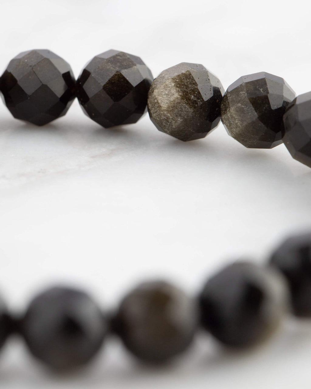 Detalle cercano de las cuentas de Obsidiana Dorada mostrando su veta dorada natural