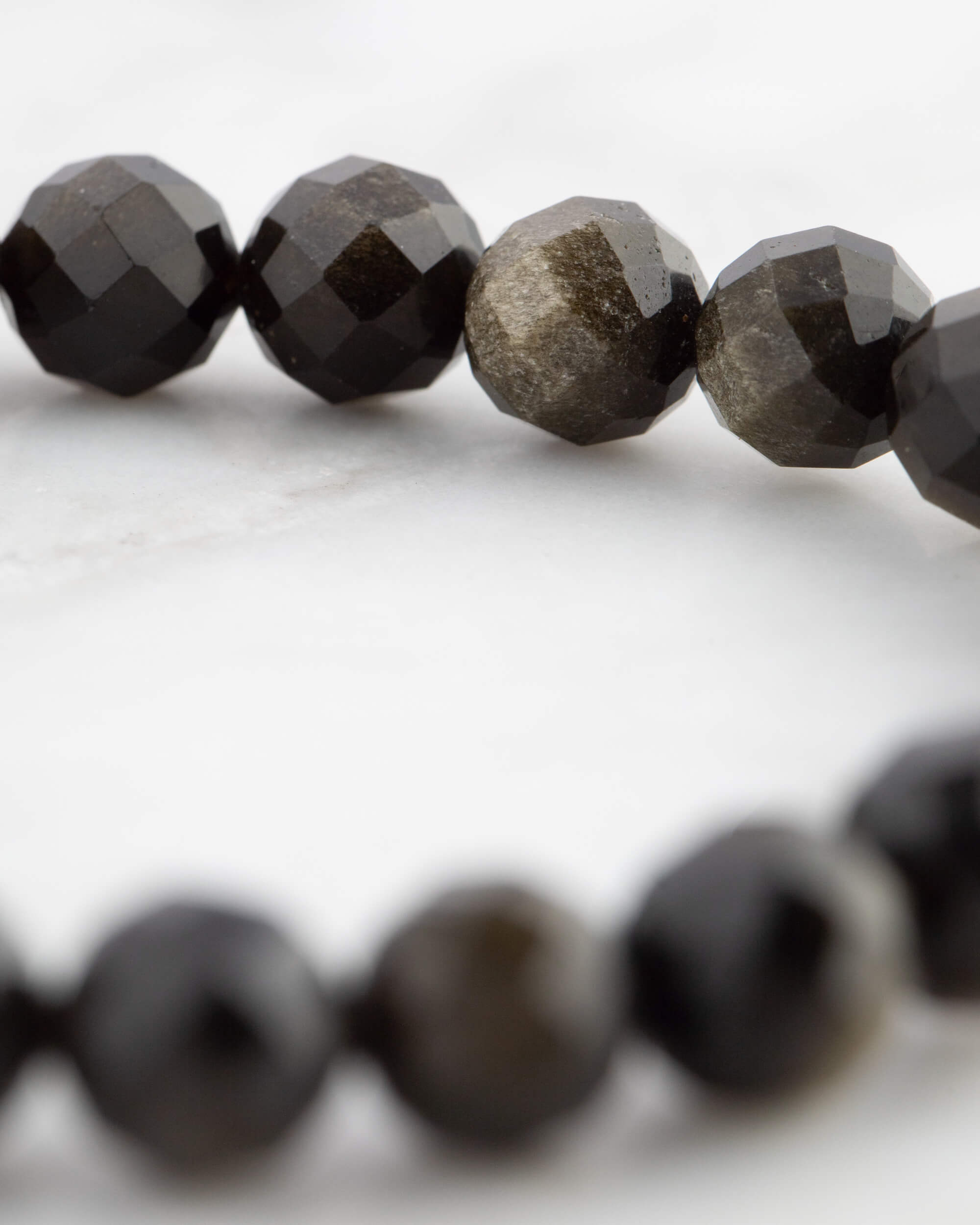 Detalle cercano de las cuentas de Obsidiana Dorada mostrando su veta dorada natural