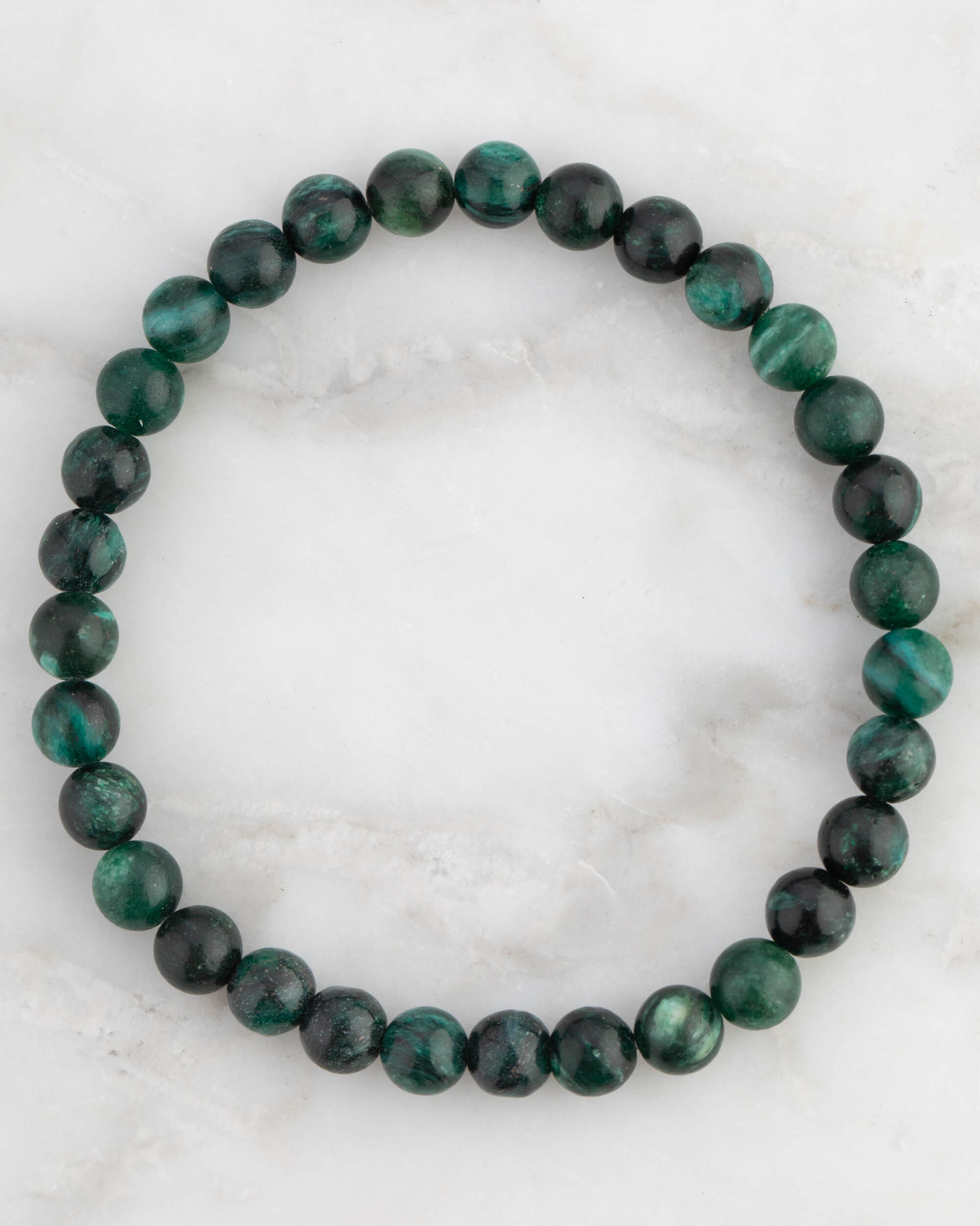 Pulsera de Esmeralda en Matriz de Biotita, pieza completa en círculo sobre mármol claro