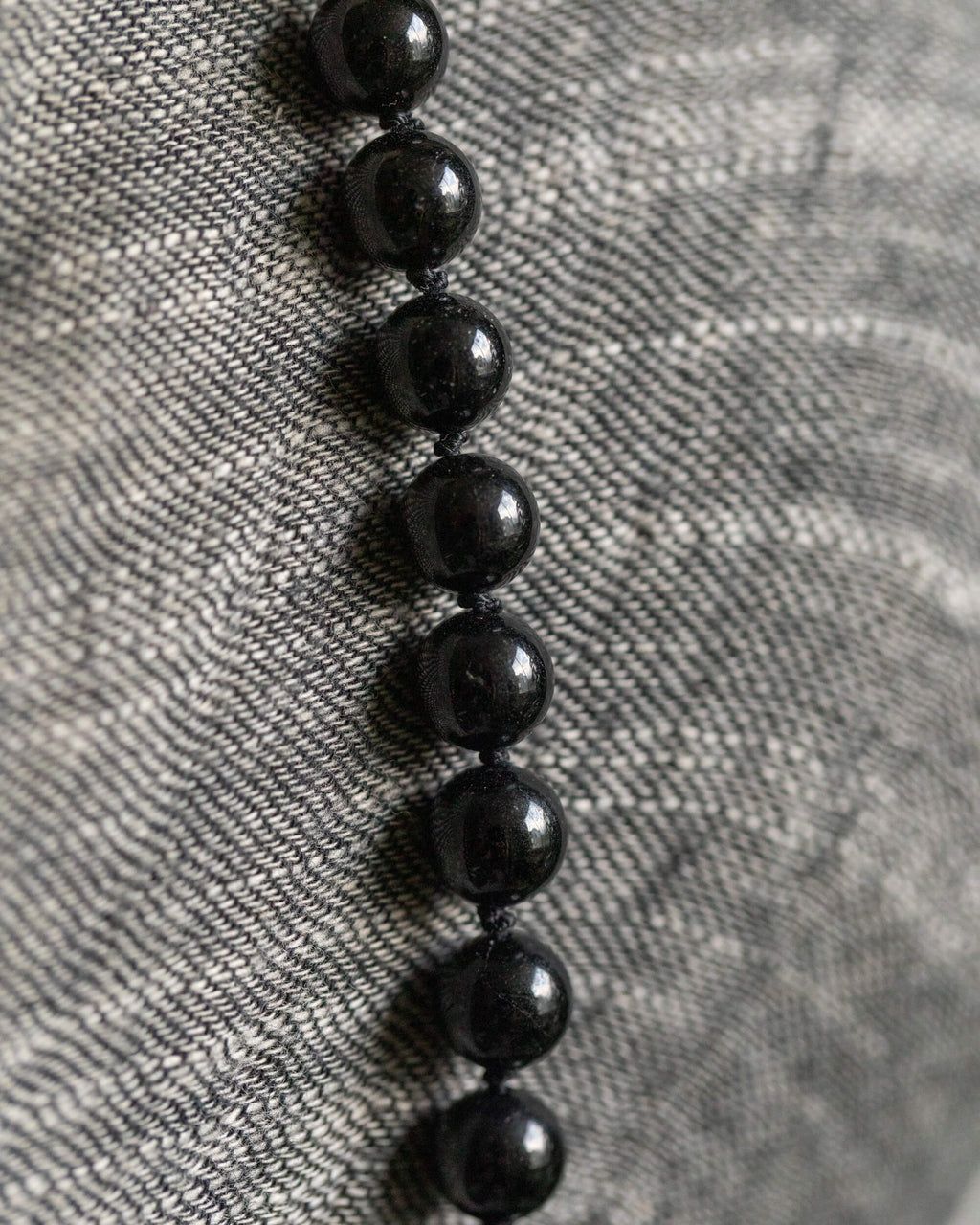 Detalle macro de las cuentas de Turmalina Negra sobre tela gris