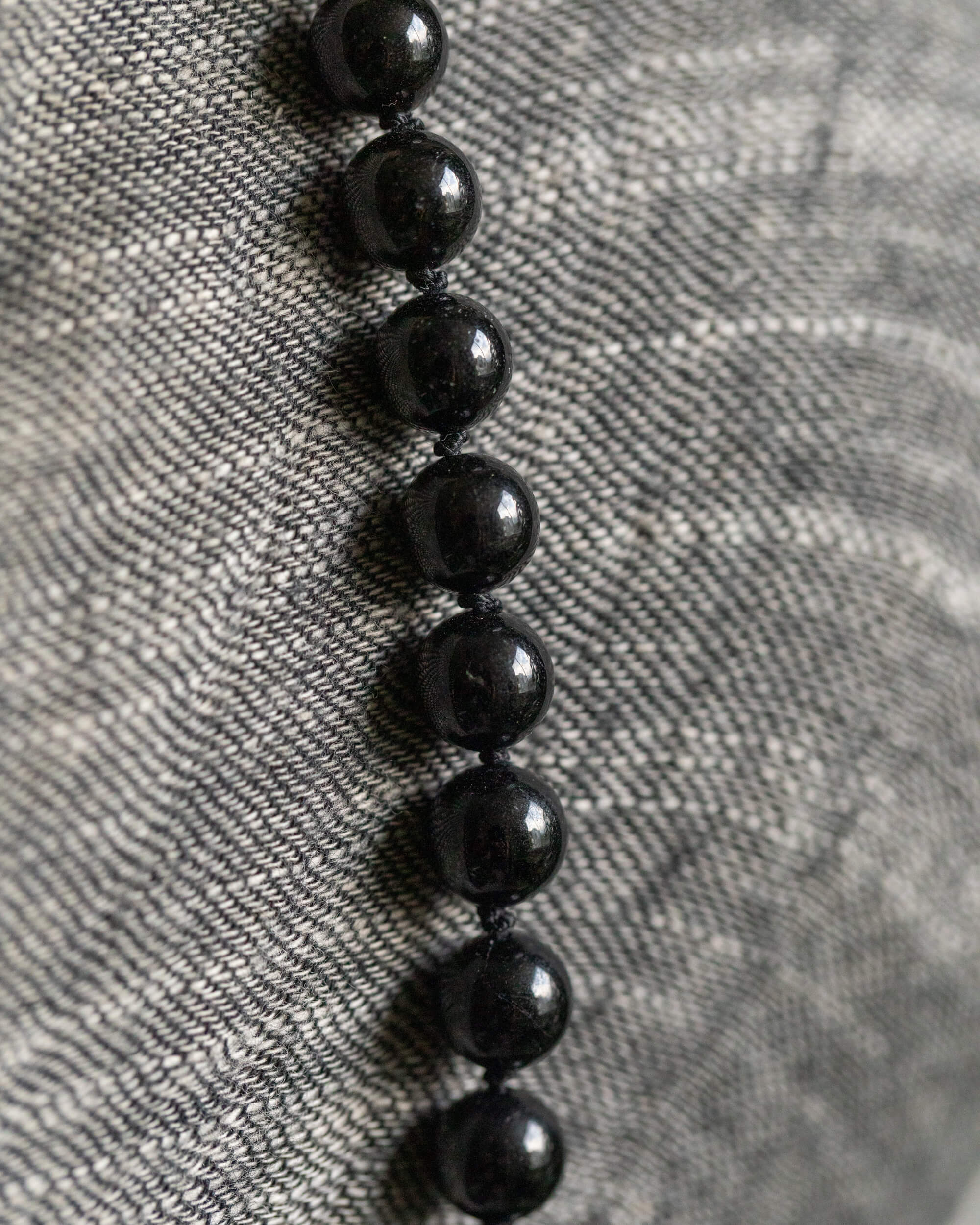 Detalle macro de las cuentas de Turmalina Negra sobre tela gris