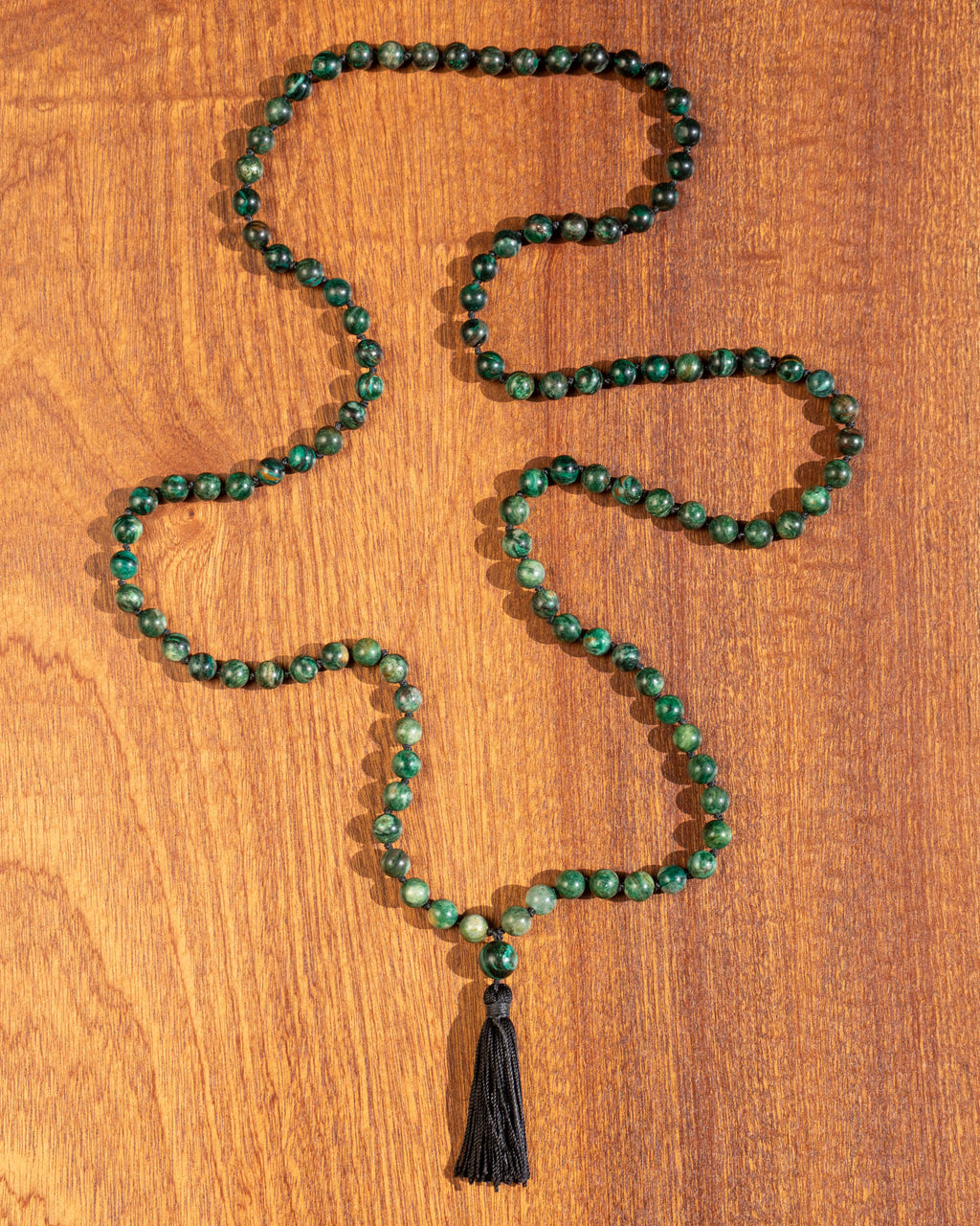 Japa mala de Esmeralda en matriz de Biotita completo en zigzag sobre madera, con borla negra