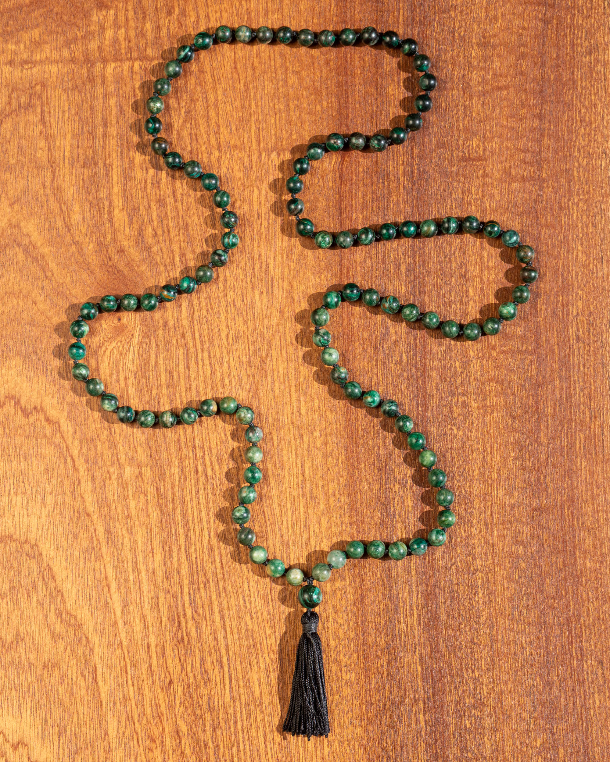 Japa mala de Esmeralda en matriz de Biotita completo en zigzag sobre madera, con borla negra