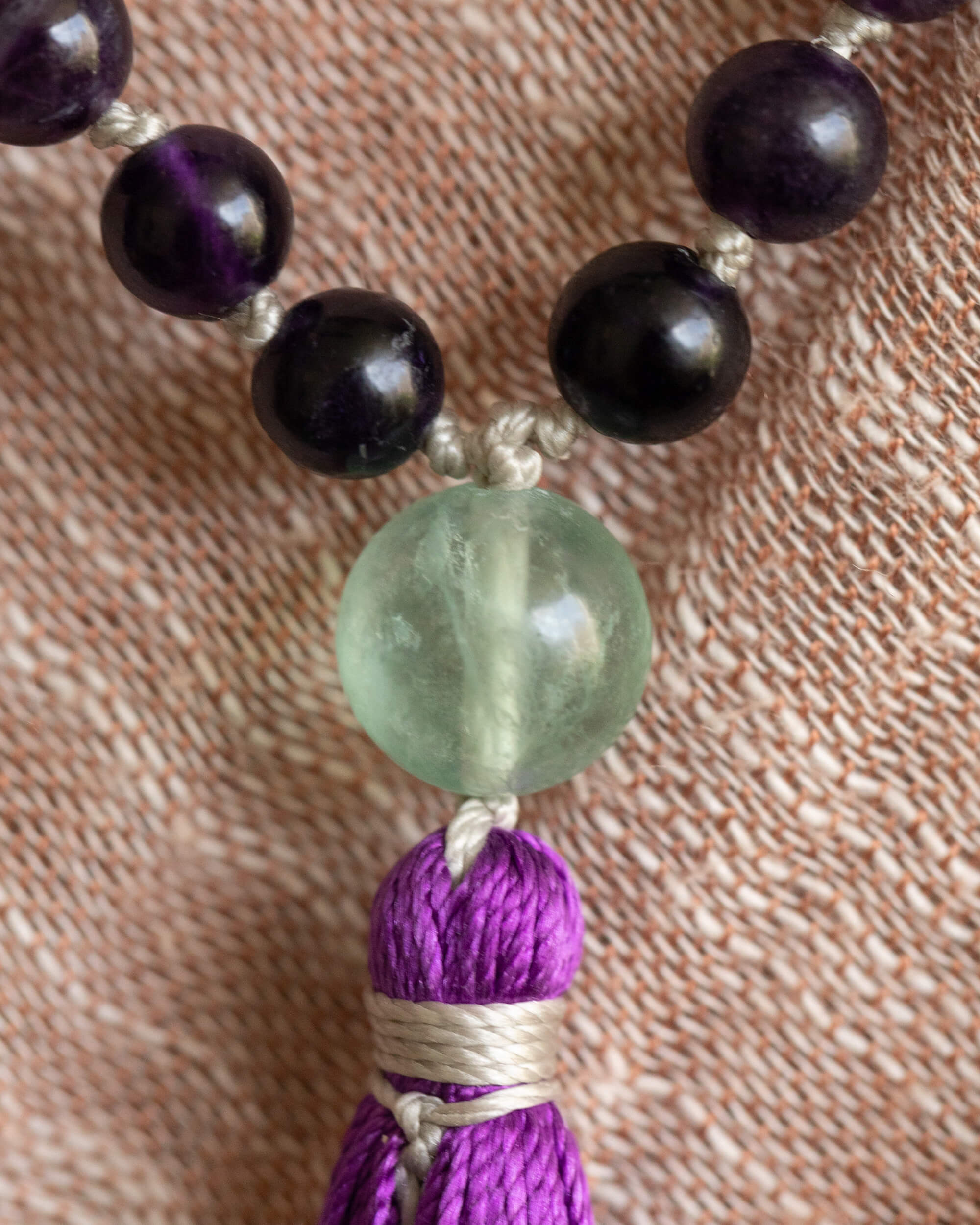 Detalle macro del guru bead de Fluorita verde y la borla morada sobre tela