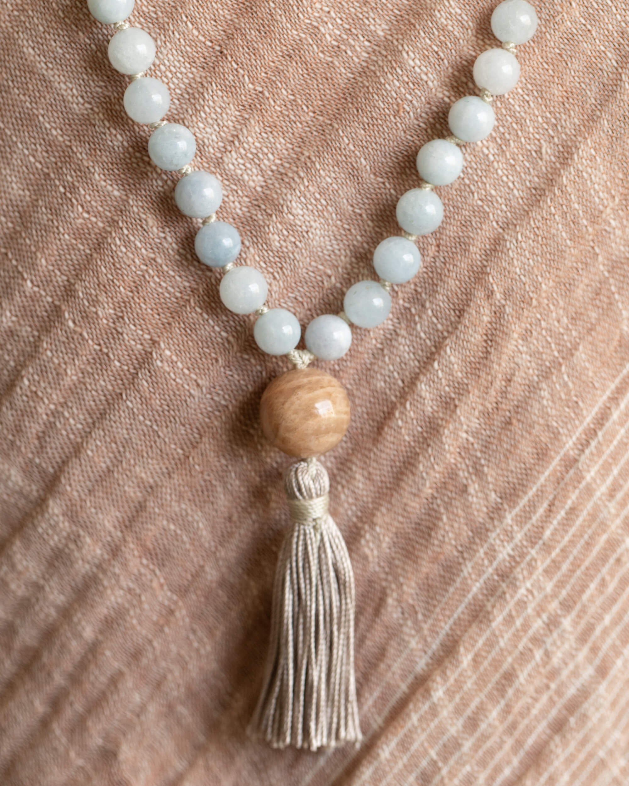 Japa Mala de Morganita, vista cercana del guru bead de madera y la borla sobre tela