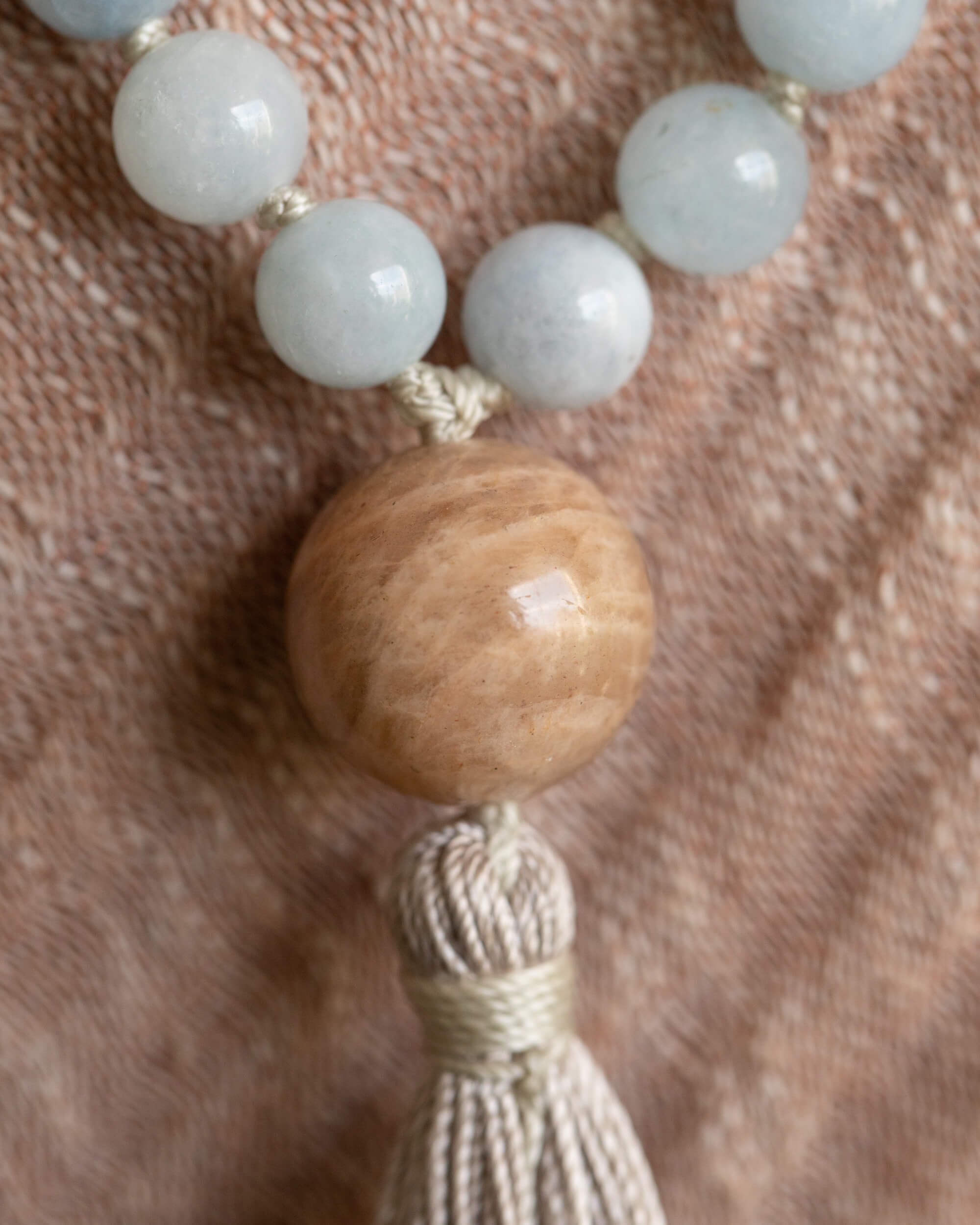 Detalle macro del guru bead de madera y borla del Japa Mala sobre tela clara