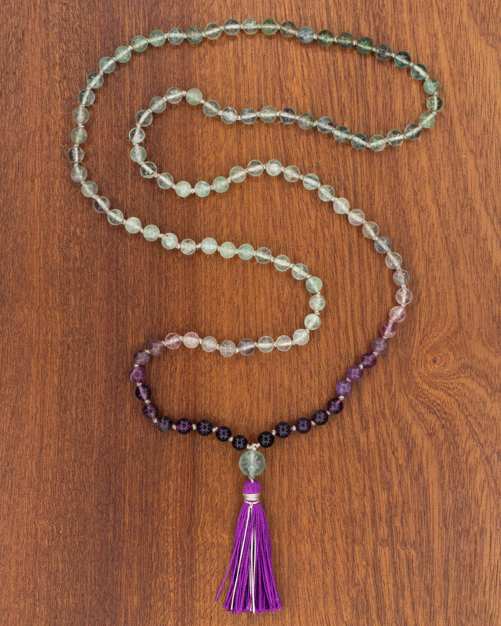 Japa Mala de Fluorita, pieza completa extendida en serpentina sobre madera
