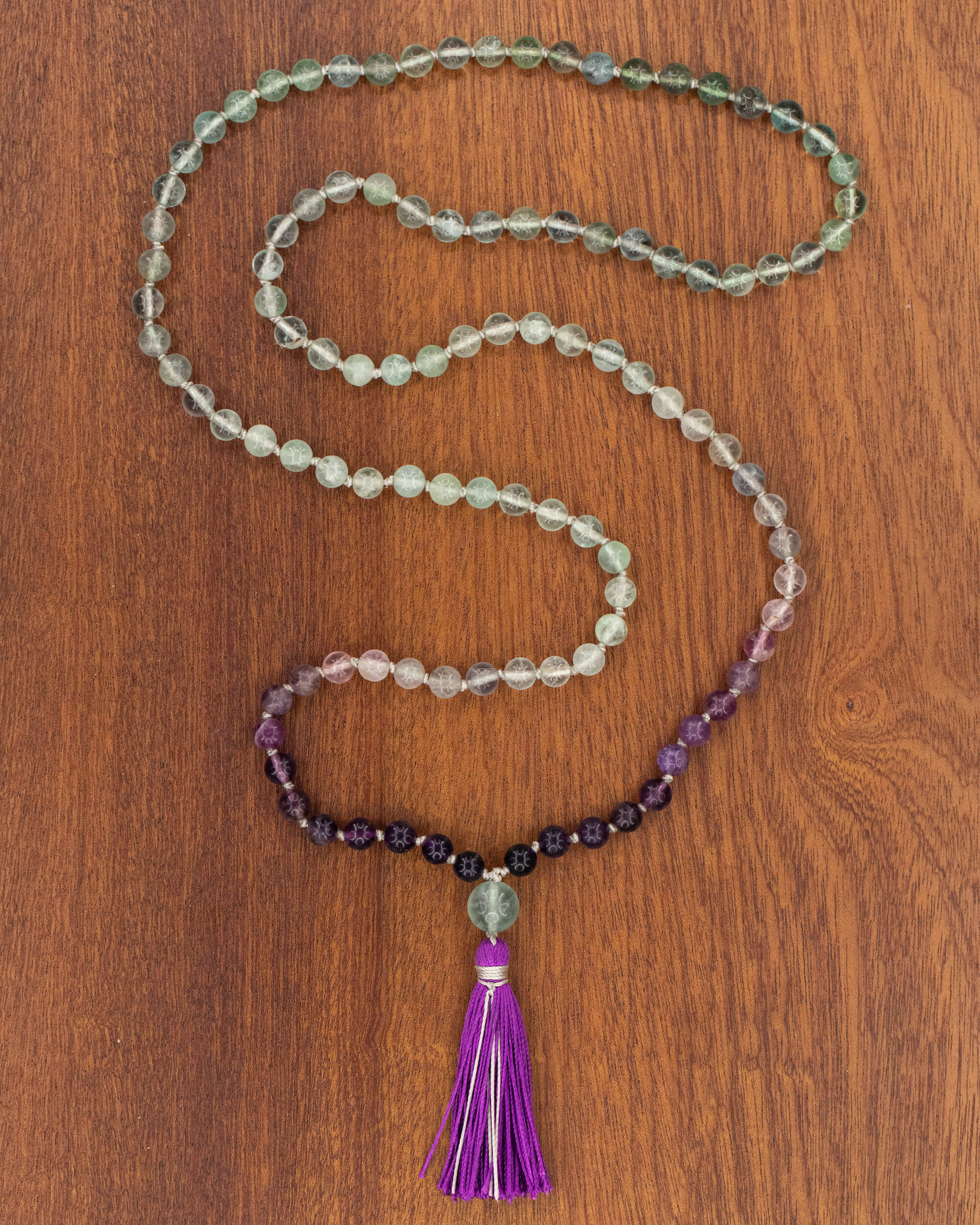 Japa Mala de Fluorita, pieza completa extendida en serpentina sobre madera