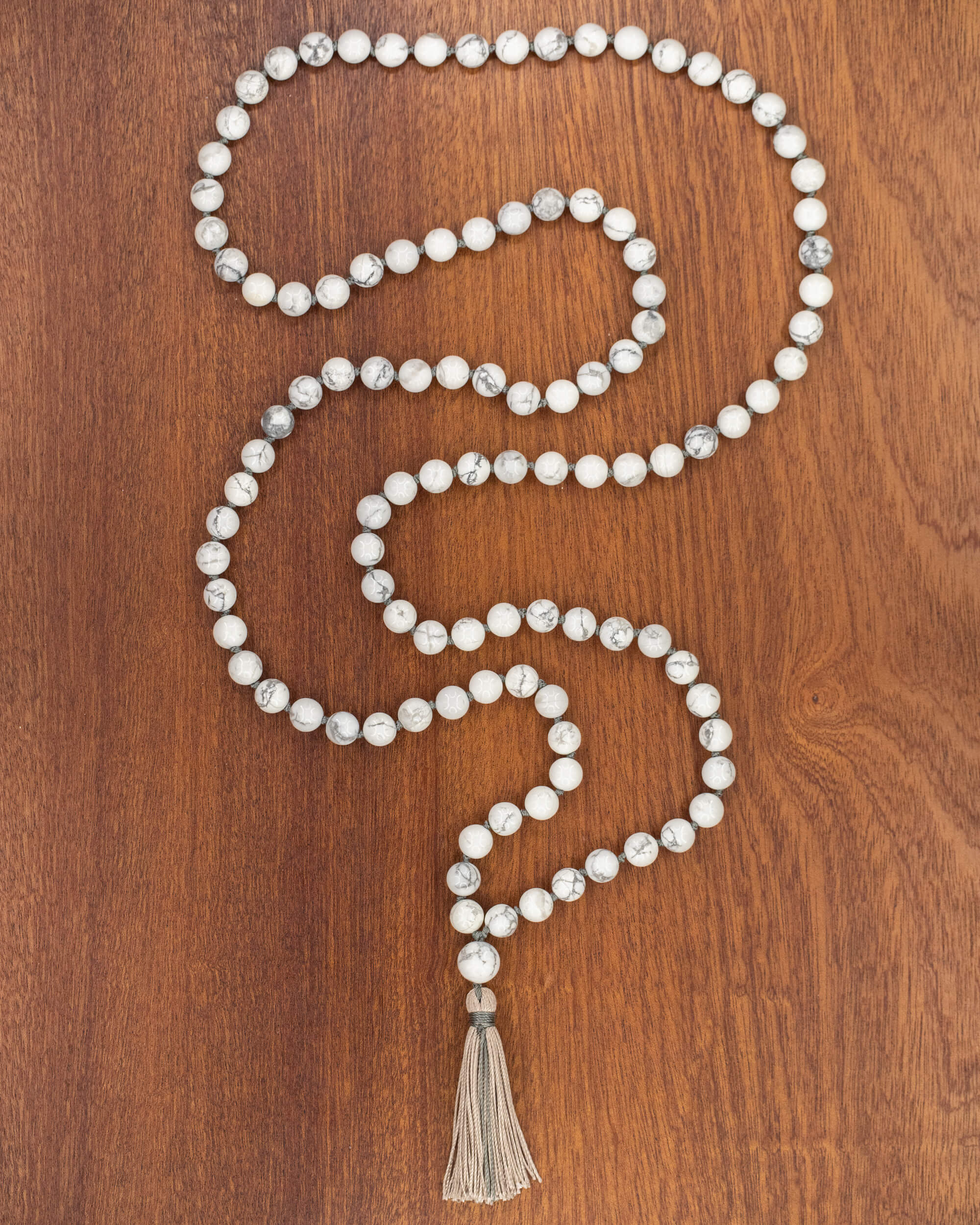 Japa Mala de Howlita, pieza completa extendida en serpentina sobre madera