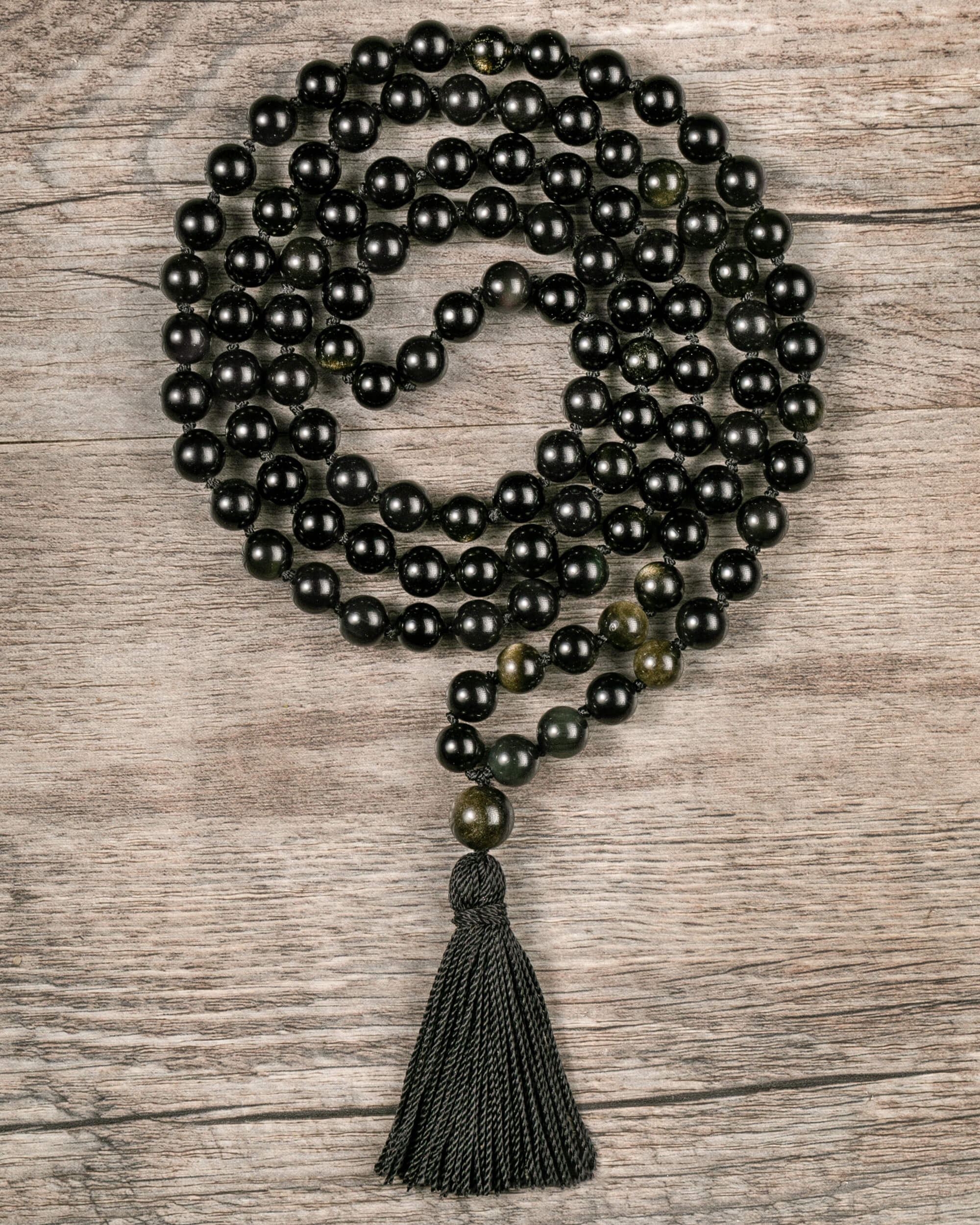 Japa Mala de Obsidiana Dorada, pieza completa enrollada sobre madera clara