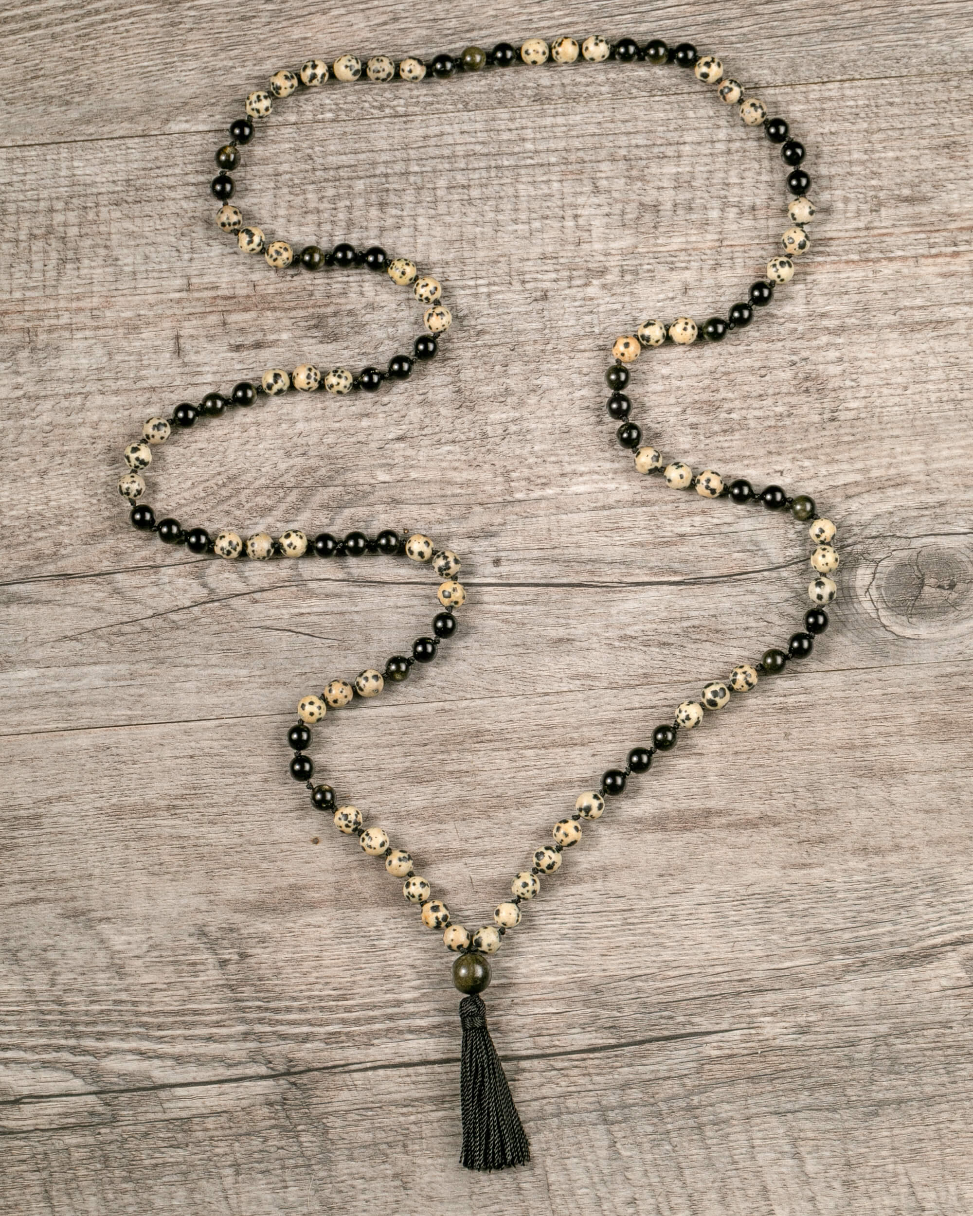 Japa Mala de Jaspe Dálmata y Obsidiana Dorada extendido en zigzag sobre madera