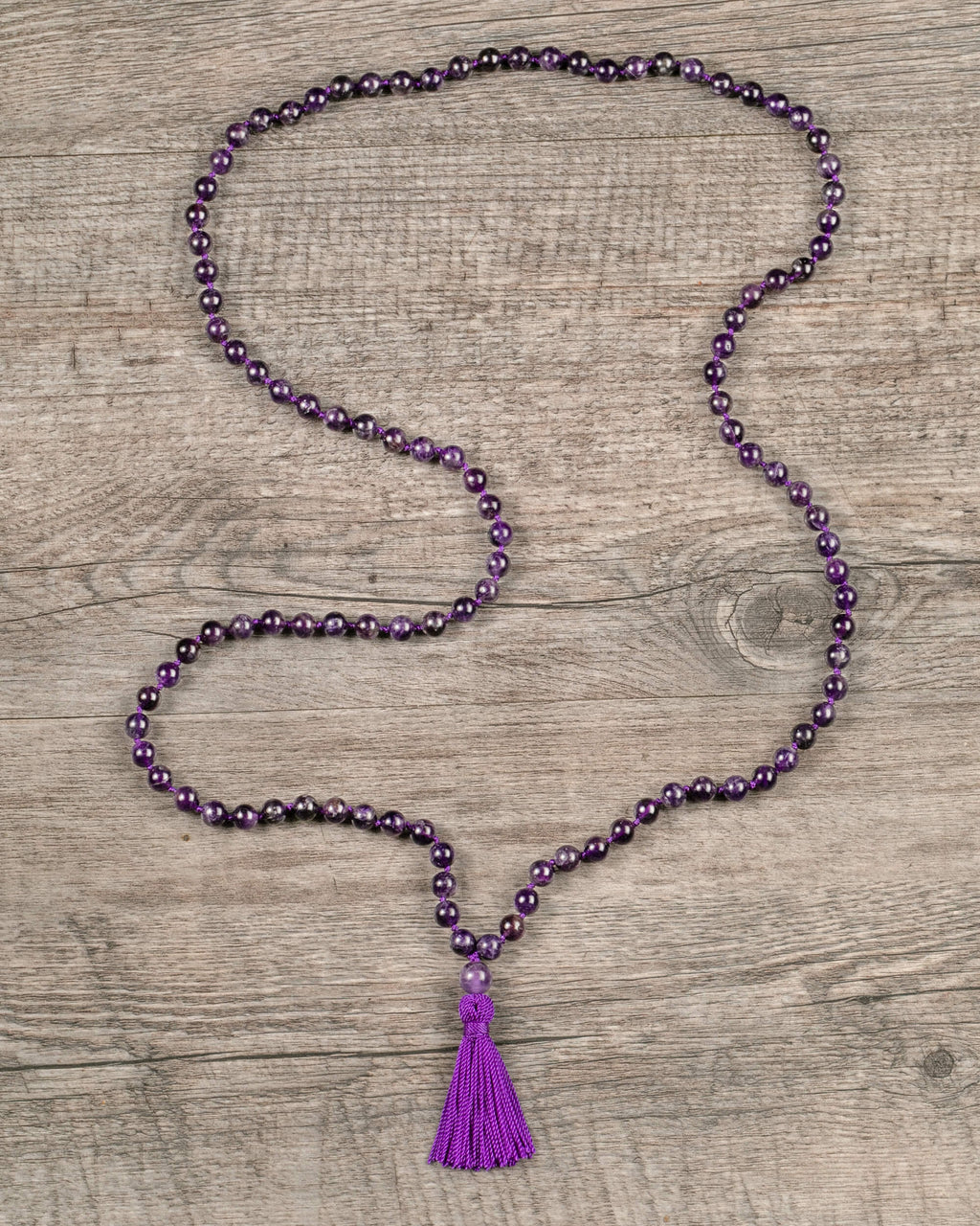 Japa Mala de Amatista extendido en zigzag sobre madera