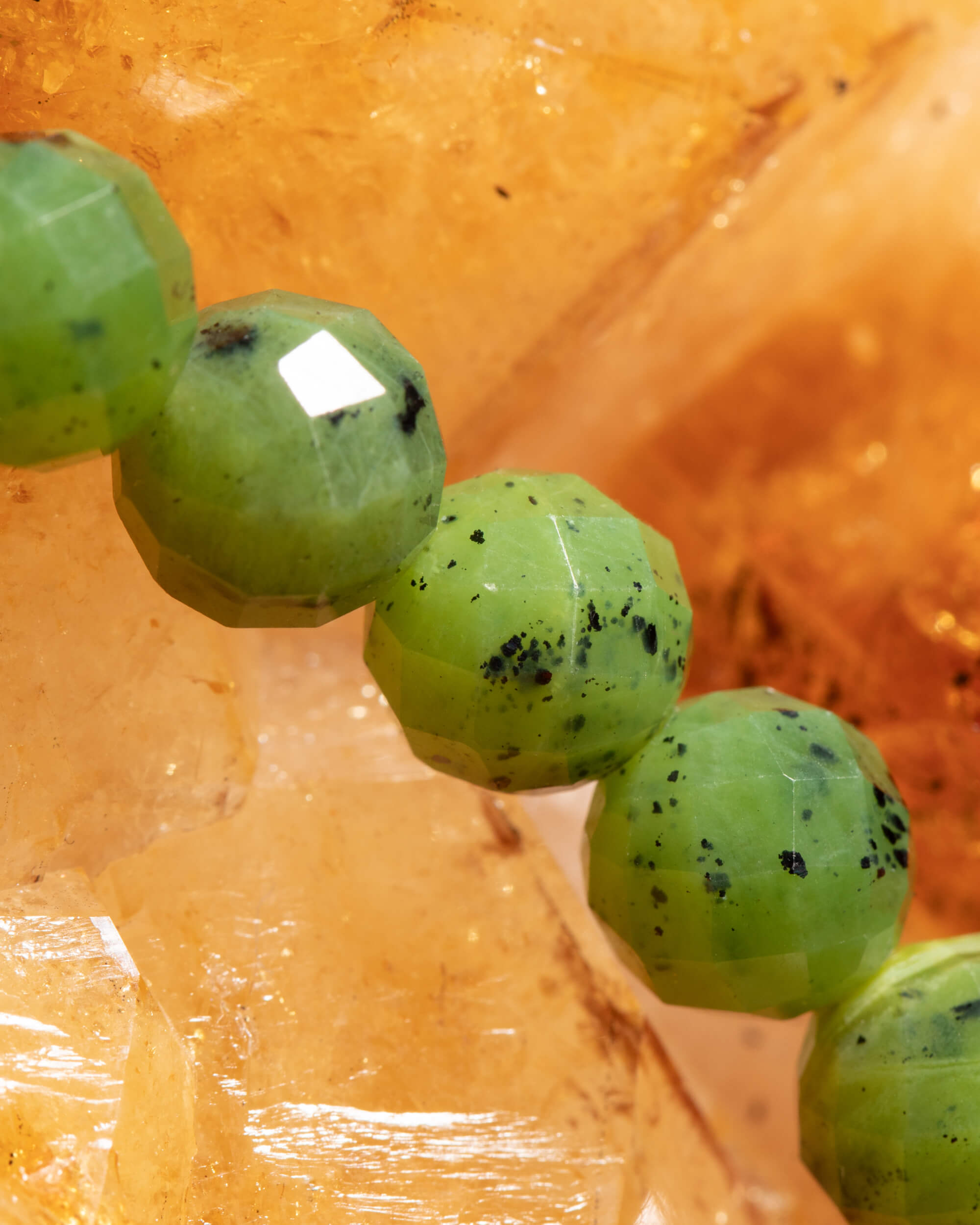 Detalle macro de las cuentas de Jade Verde con motas oscuras sobre citrino