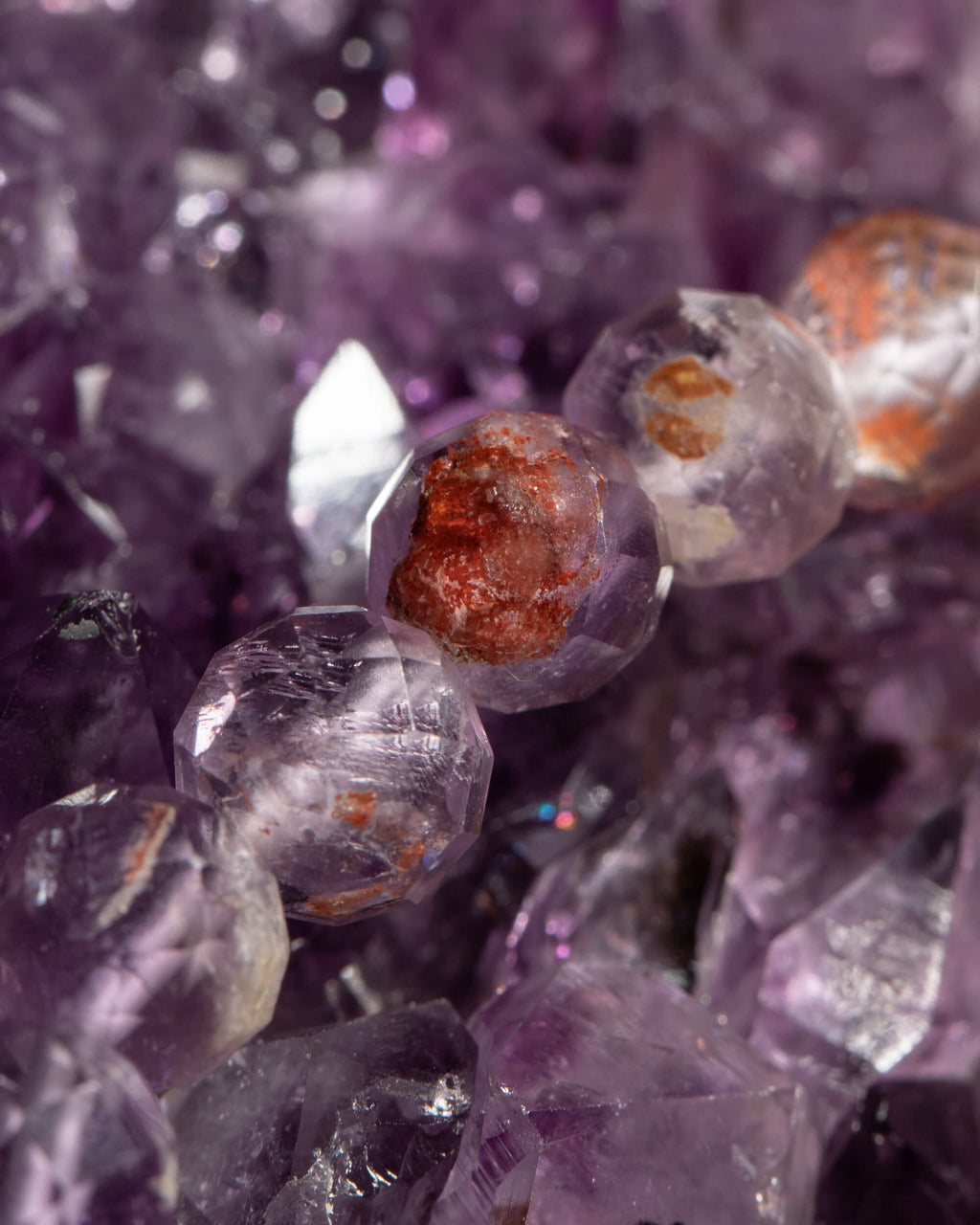 Detalle macro de las cuentas de Amatista Fantasma con inclusiones sobre druza de amatista