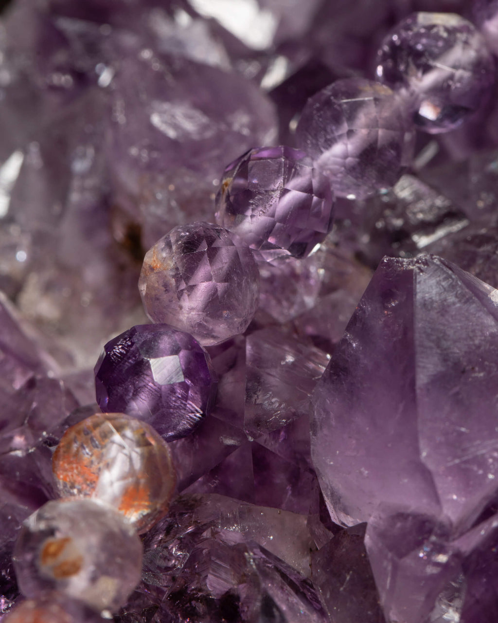 Detalle macro de las cuentas facetadas de Amatista Fantasma sobre druza de amatista
