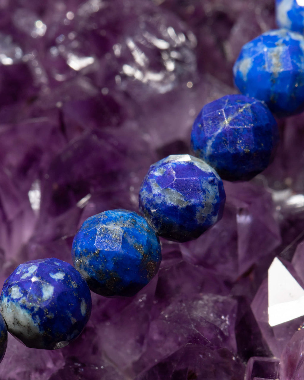 Detalle macro de las cuentas facetadas de Lapislázuli sobre cristales de amatista