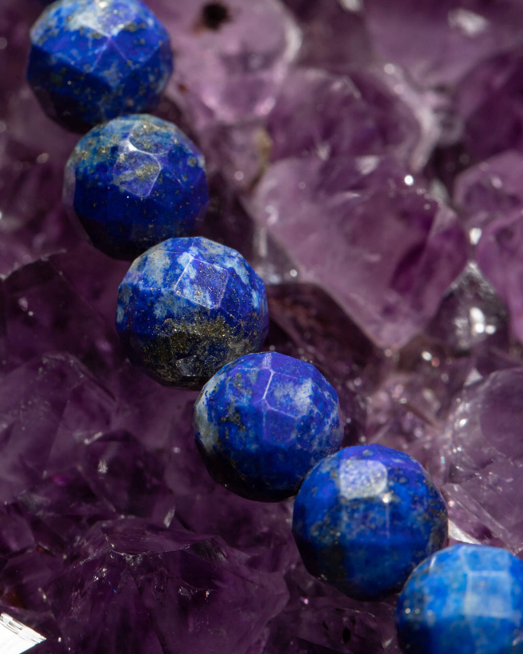 Detalle macro de las cuentas facetadas de Lapislázuli sobre cristales de amatista