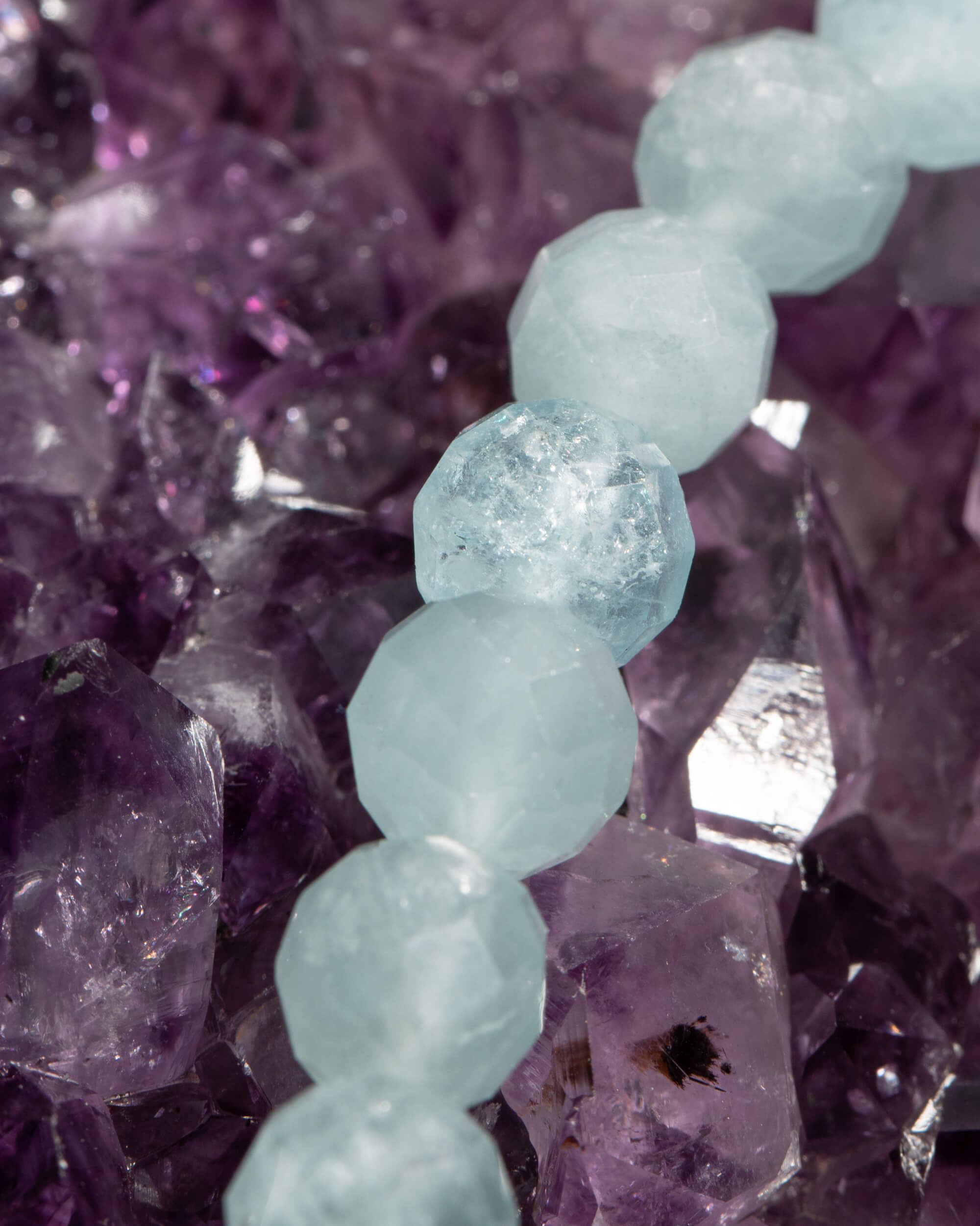 Detalle macro de las cuentas facetadas de Aguamarina con su transparencia, sobre amatista