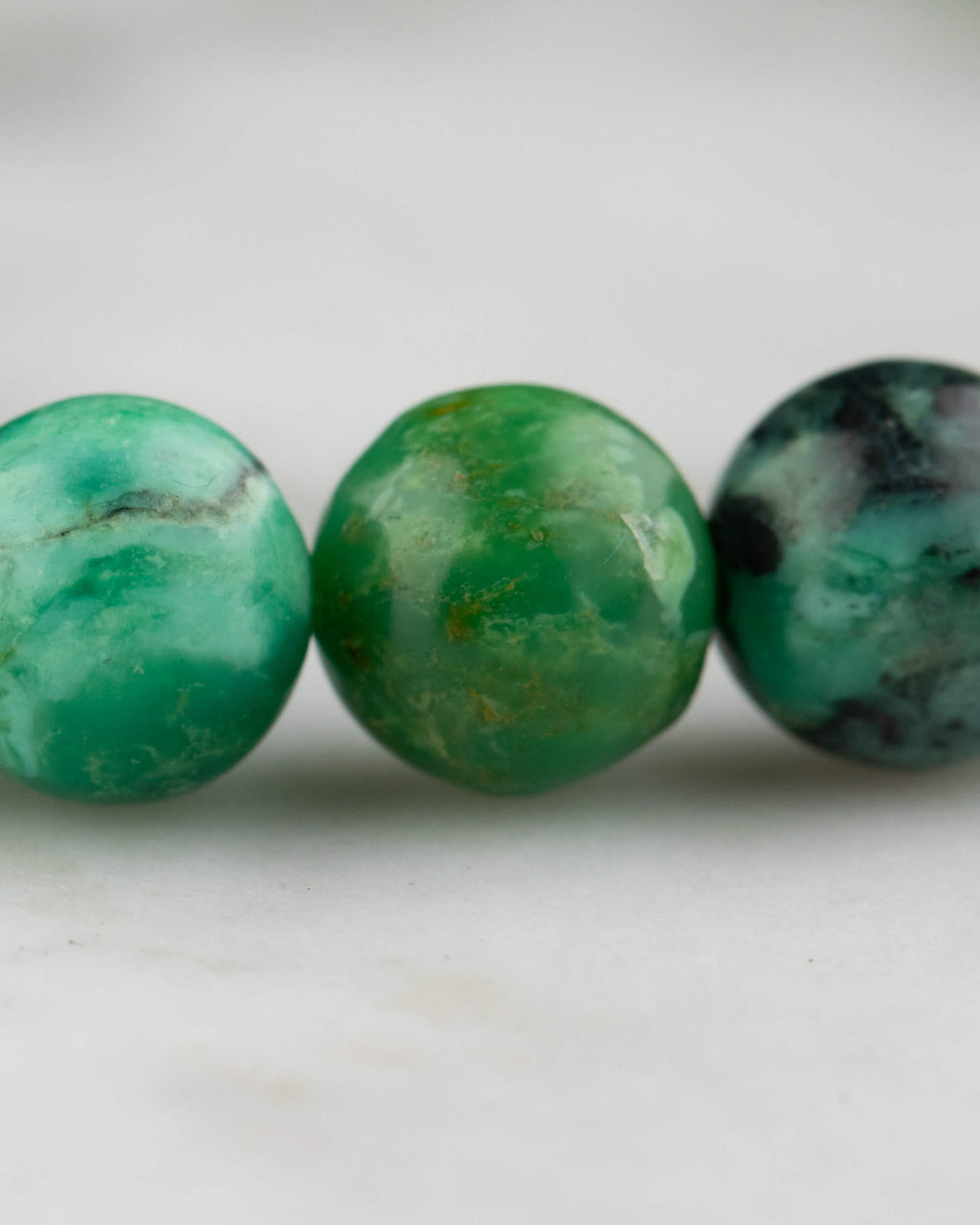 Detalle macro de tres cuentas de Variscita en distintos tonos de verde