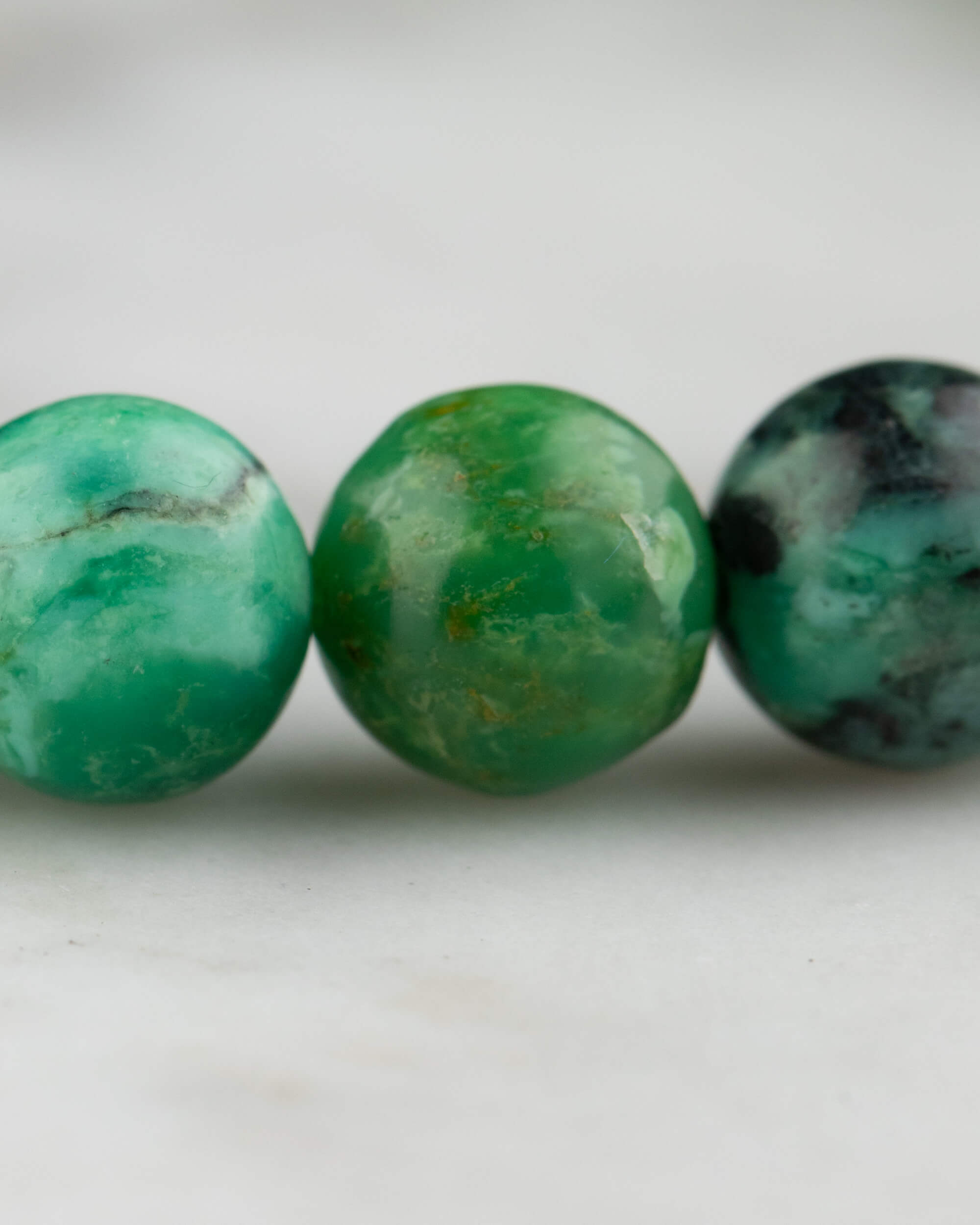Detalle macro de tres cuentas de Variscita en distintos tonos de verde