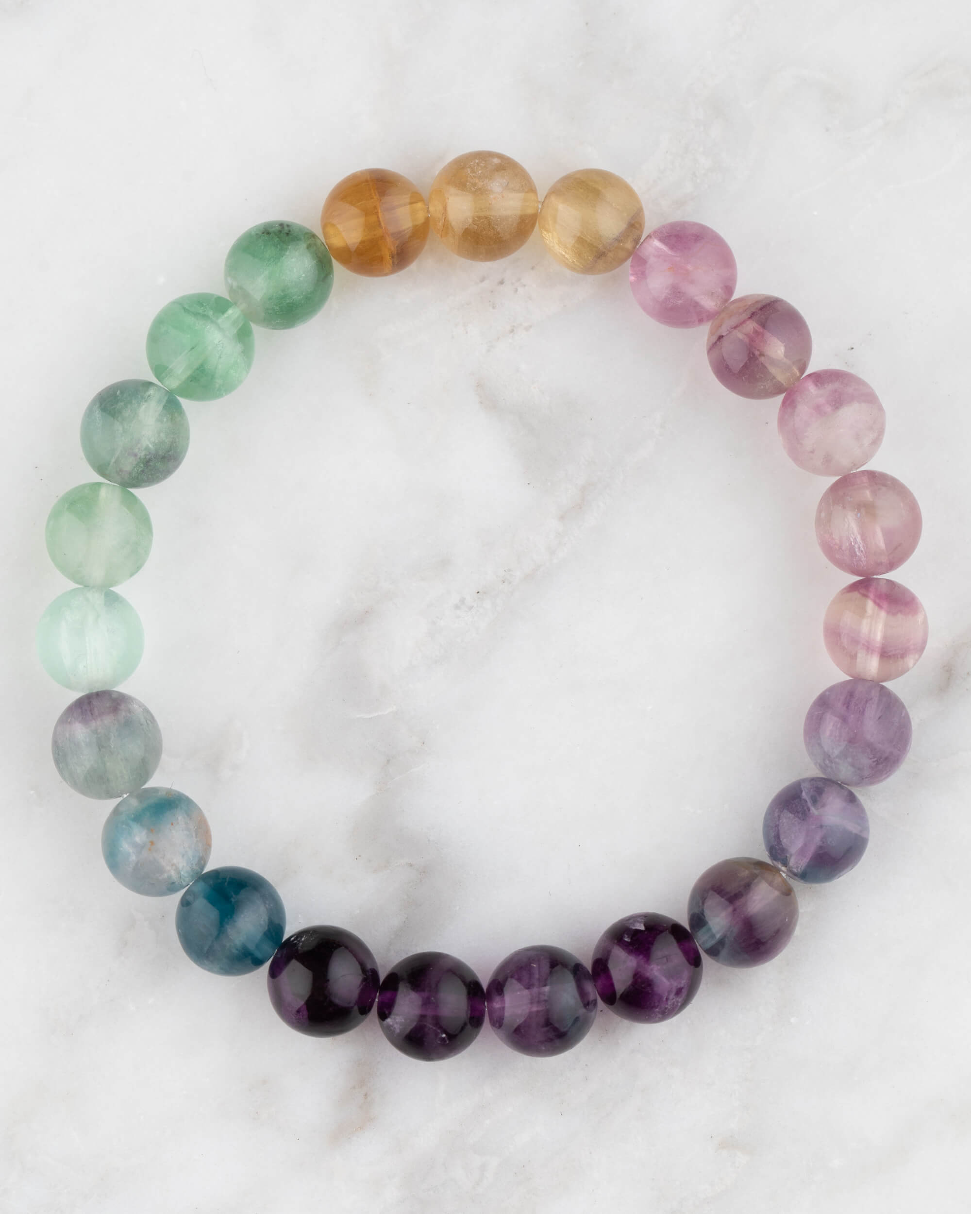 Pulsera de Fluorita Arcoiris de 8 mm, pieza completa con degradado de colores sobre mármol claro