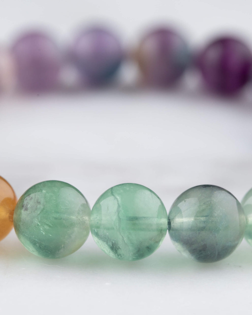 Detalle de las cuentas de Fluorita Arcoiris, verde translucido junto a tonos ambar y morado