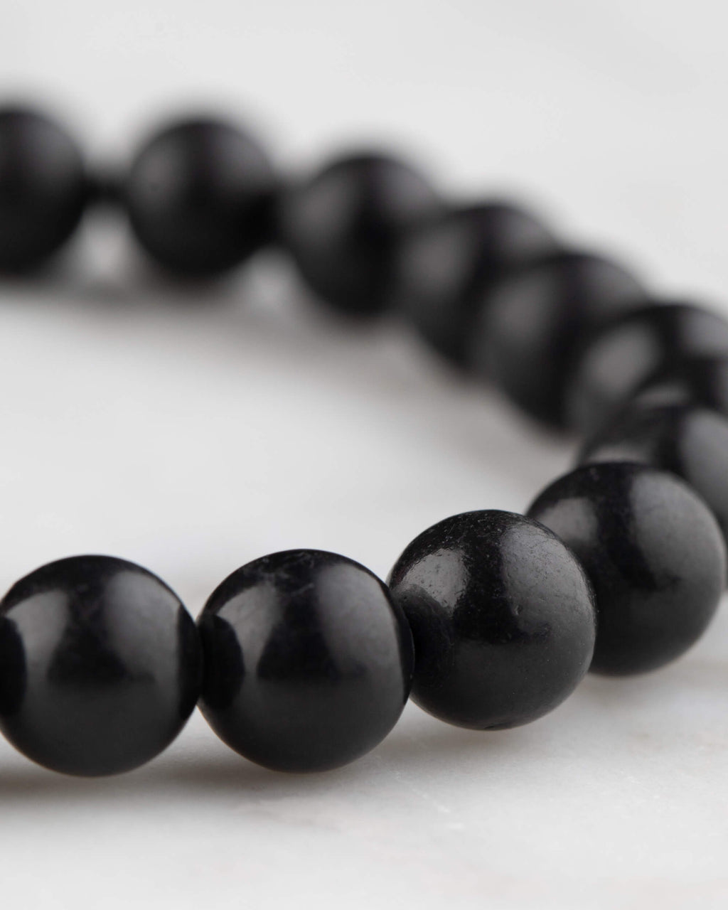 Pulsera de Shungita en angulo, cuentas negras con reflejo suave de luz