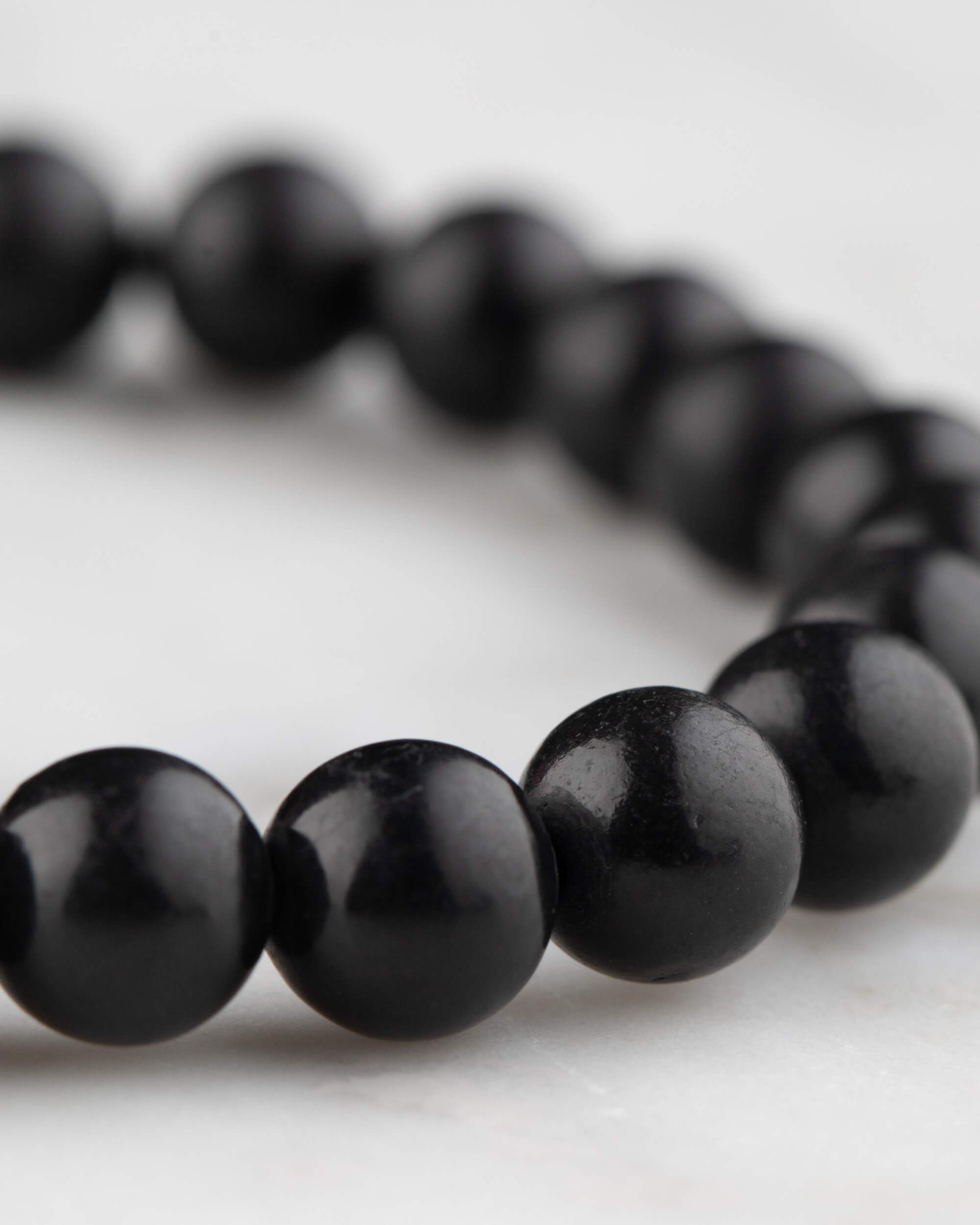 Pulsera de Shungita en angulo, cuentas negras con reflejo suave de luz