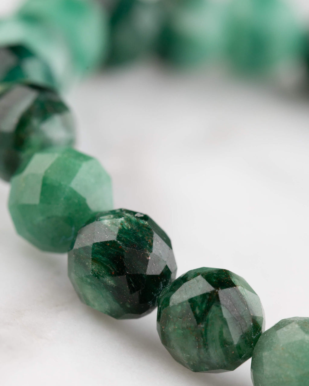 Pulsera de Esmeralda facetada vista en angulo, cuentas verdes con brillo de las facetas