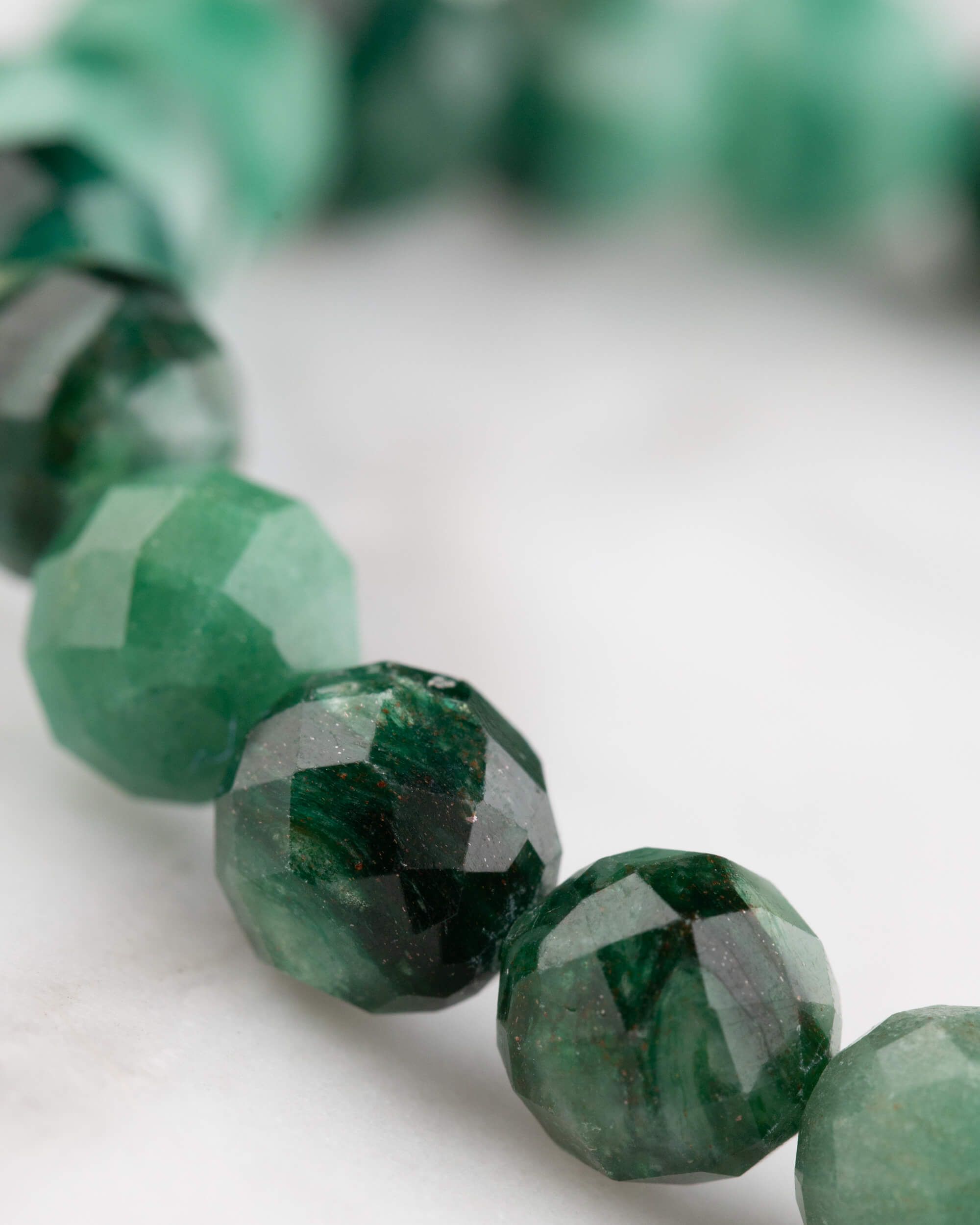 Pulsera de Esmeralda facetada vista en angulo, cuentas verdes con brillo de las facetas