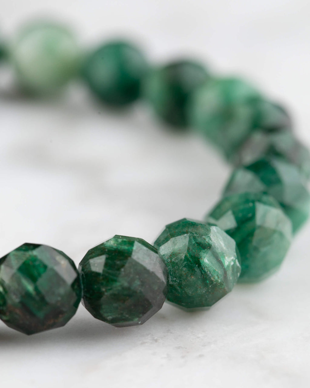 Detalle de las cuentas facetadas de Esmeralda en curva, verde intenso con vetas naturales