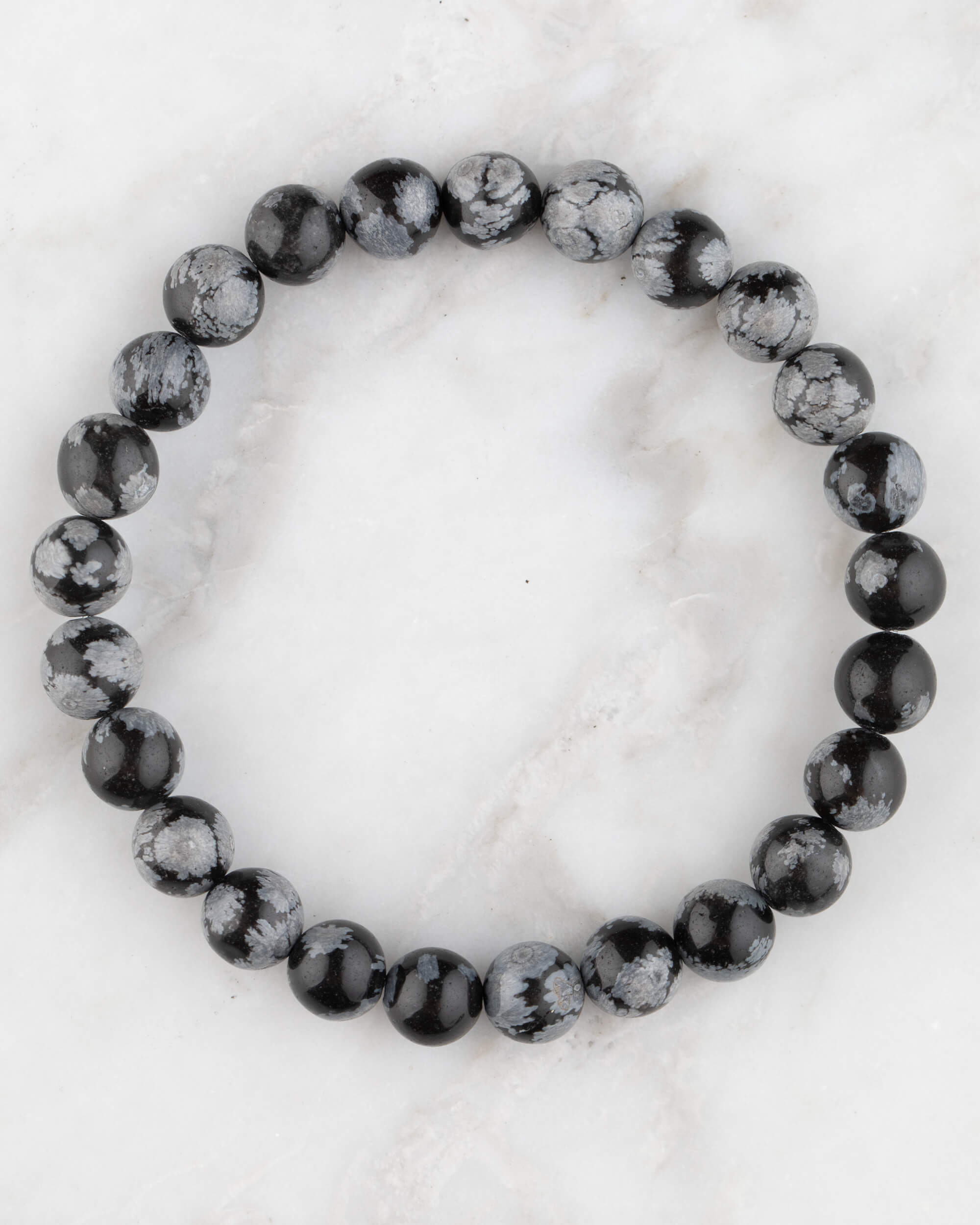 Pulsera de Obsidiana Copo de Nieve de 8 mm, pieza completa en círculo sobre mármol claro