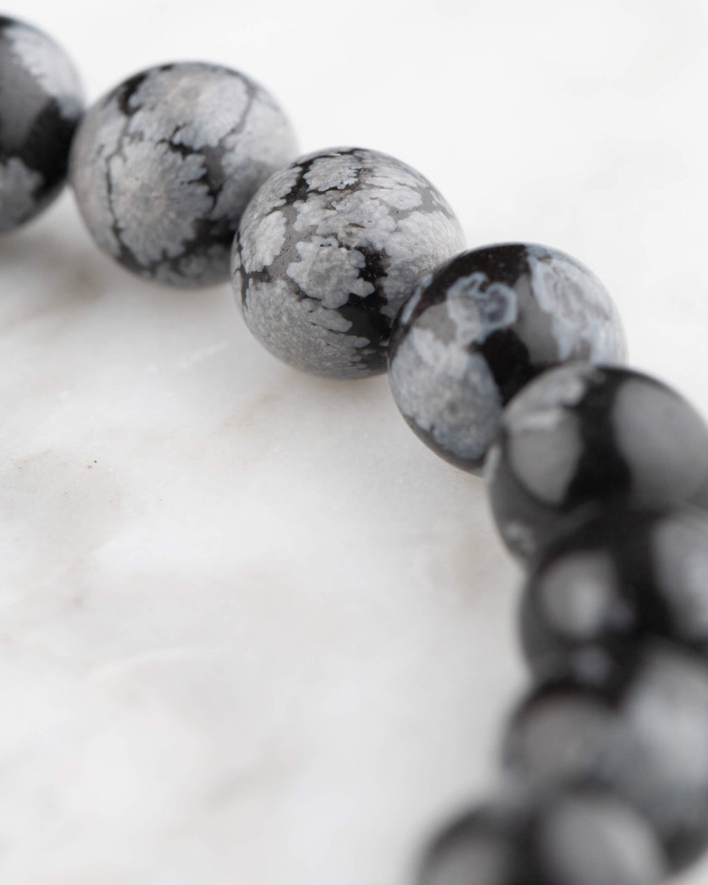 Detalle macro de las cuentas de Obsidiana Copo de Nieve, negras con manchas grises