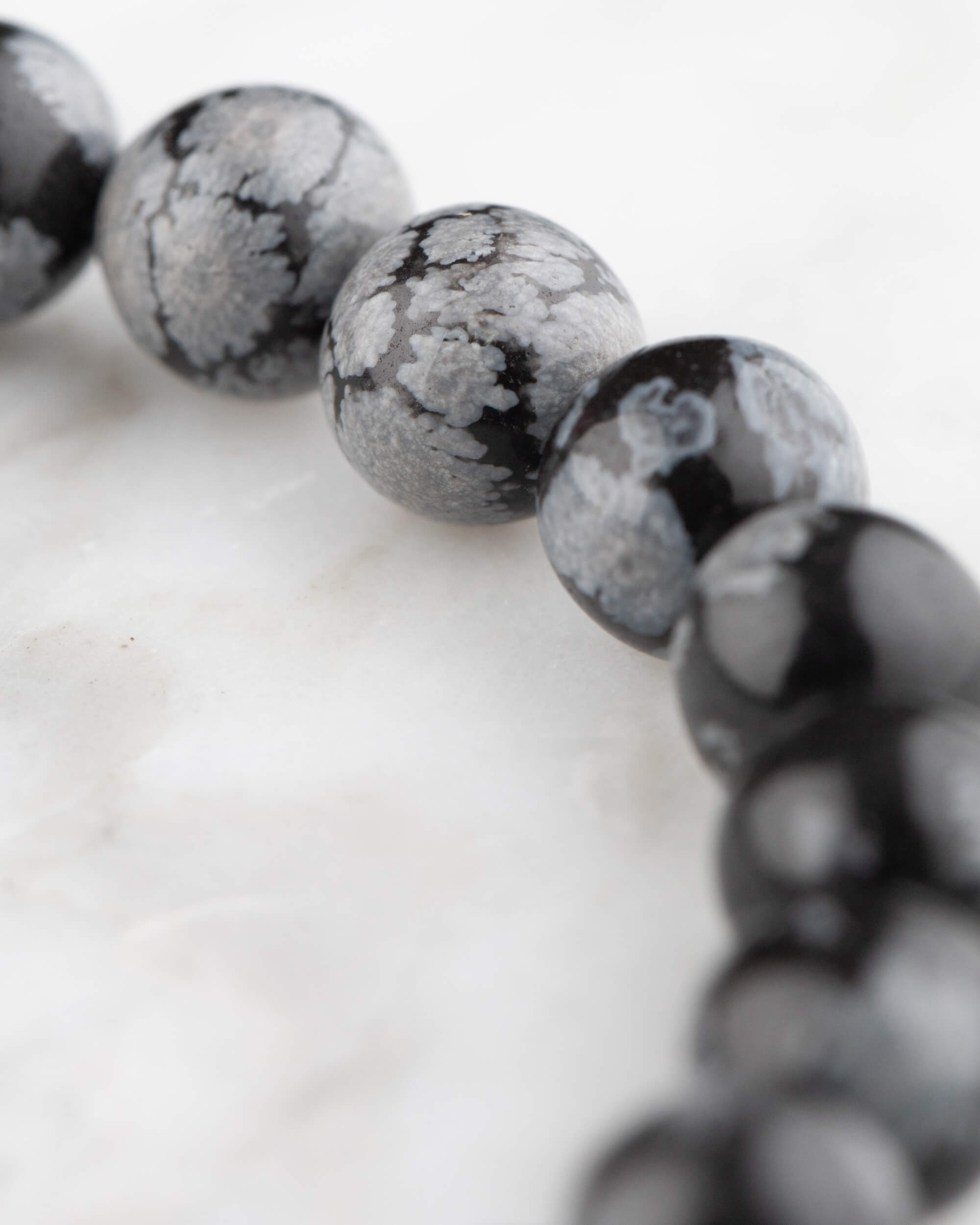 Detalle macro de las cuentas de Obsidiana Copo de Nieve, negras con manchas grises