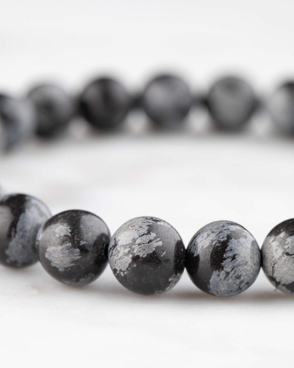 Pulsera de Obsidiana Copo de Nieve vista en angulo, textura negra y gris de las cuentas