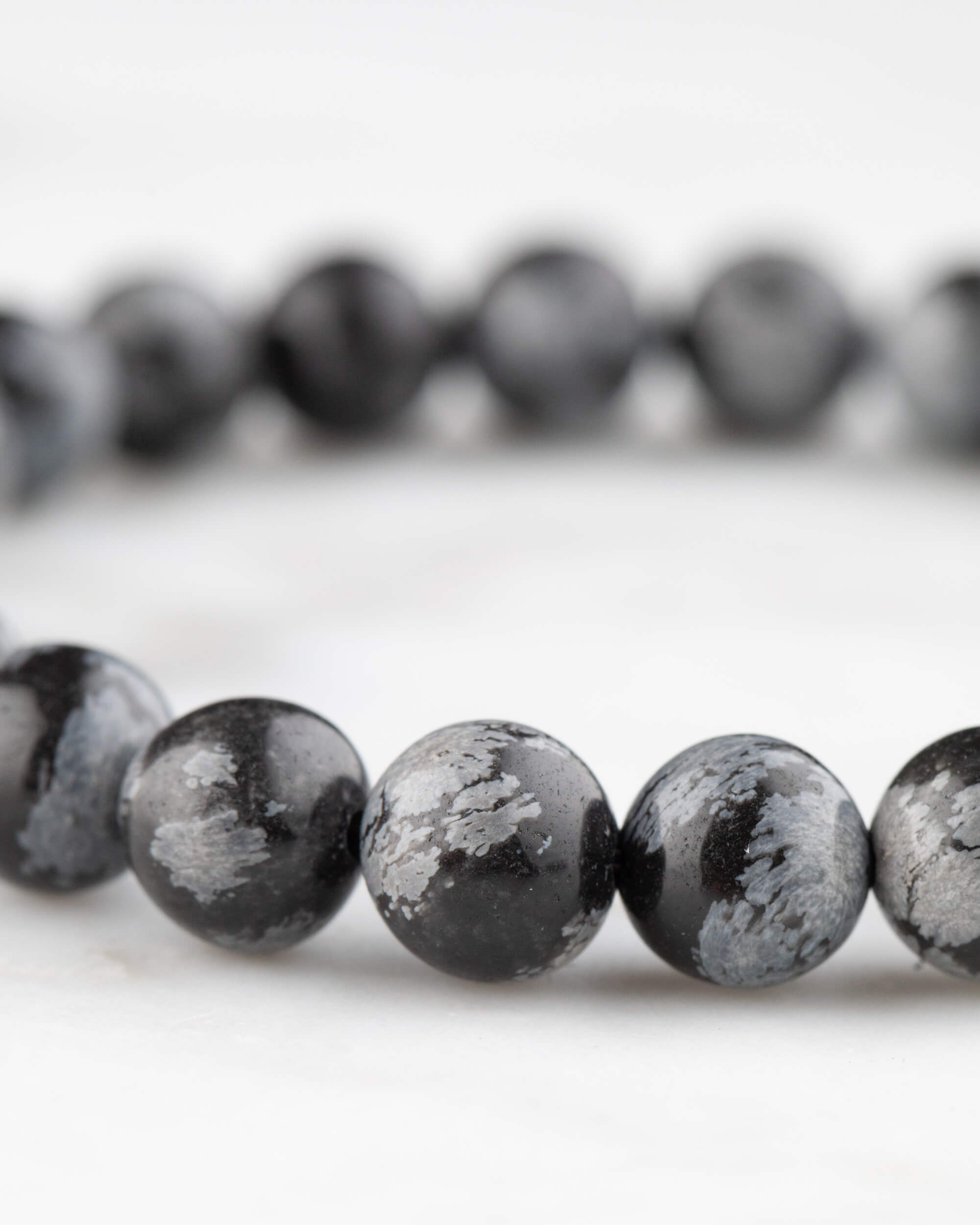 Pulsera de Obsidiana Copo de Nieve vista en angulo, textura negra y gris de las cuentas