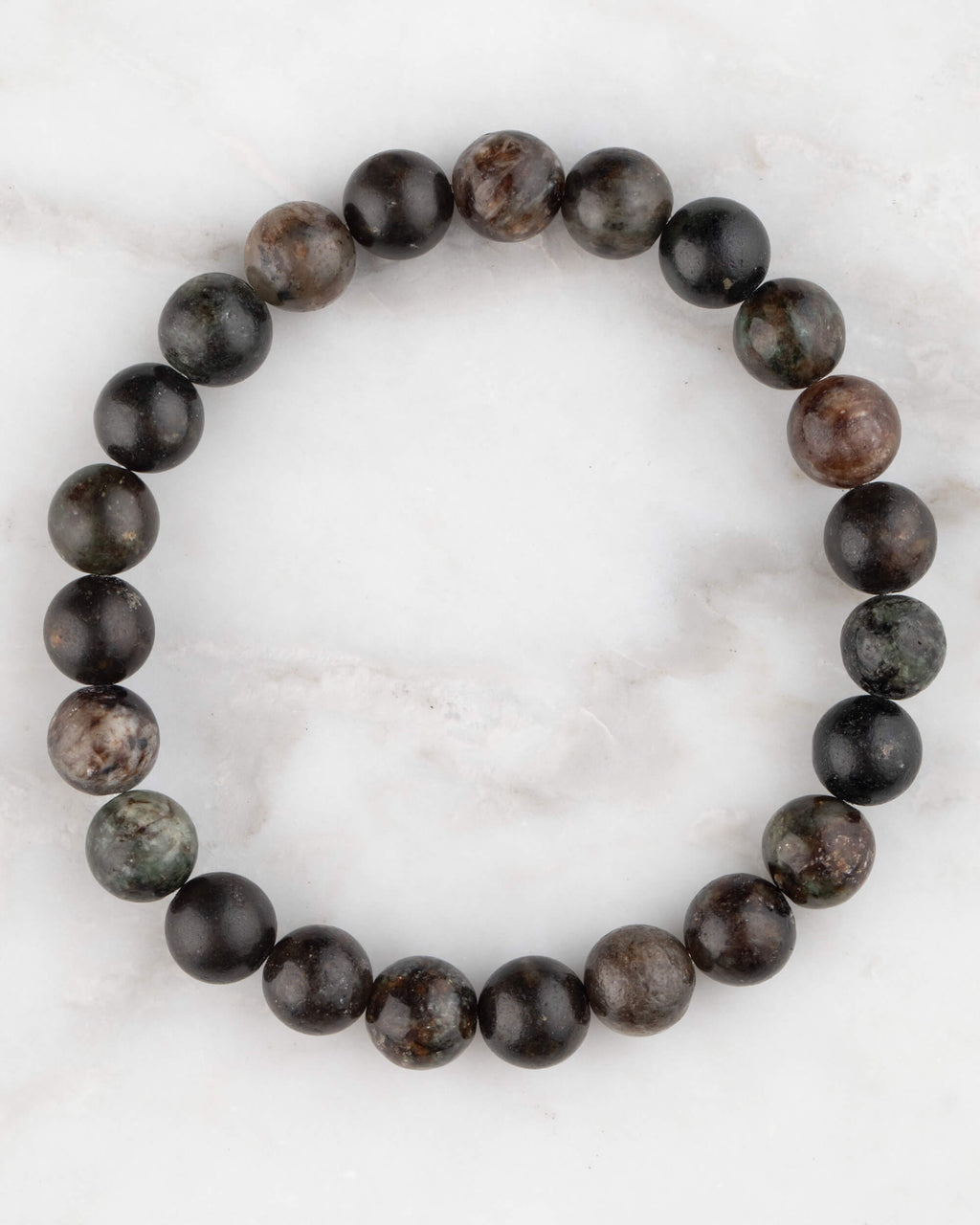 Pulsera de Flogopita de 8 mm, pieza completa en círculo con tonos oscuros sobre mármol claro