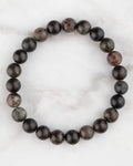 Pulsera de Flogopita de 8 mm, pieza completa en círculo con tonos oscuros sobre mármol claro