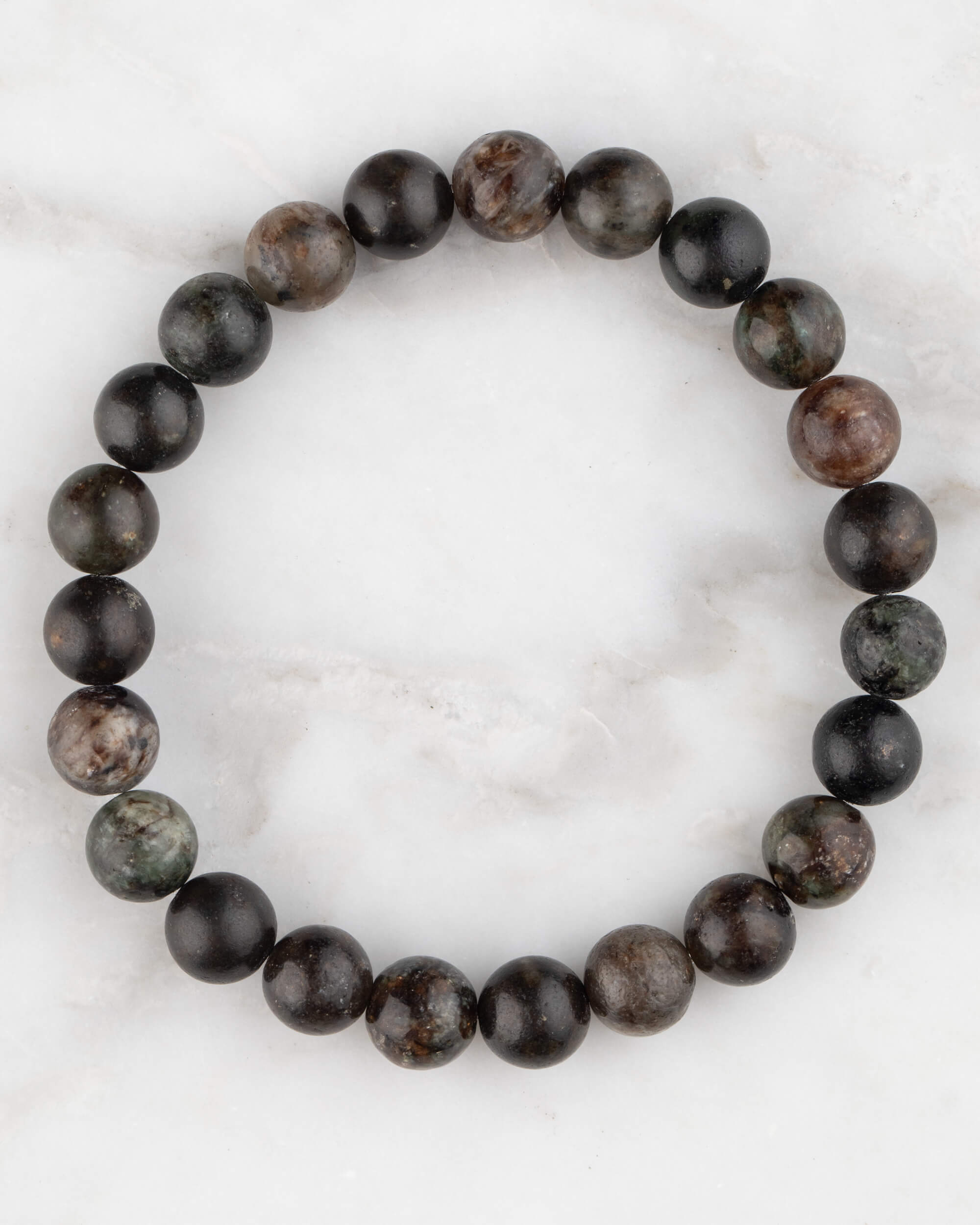 Pulsera de Flogopita de 8 mm, pieza completa en círculo con tonos oscuros sobre mármol claro