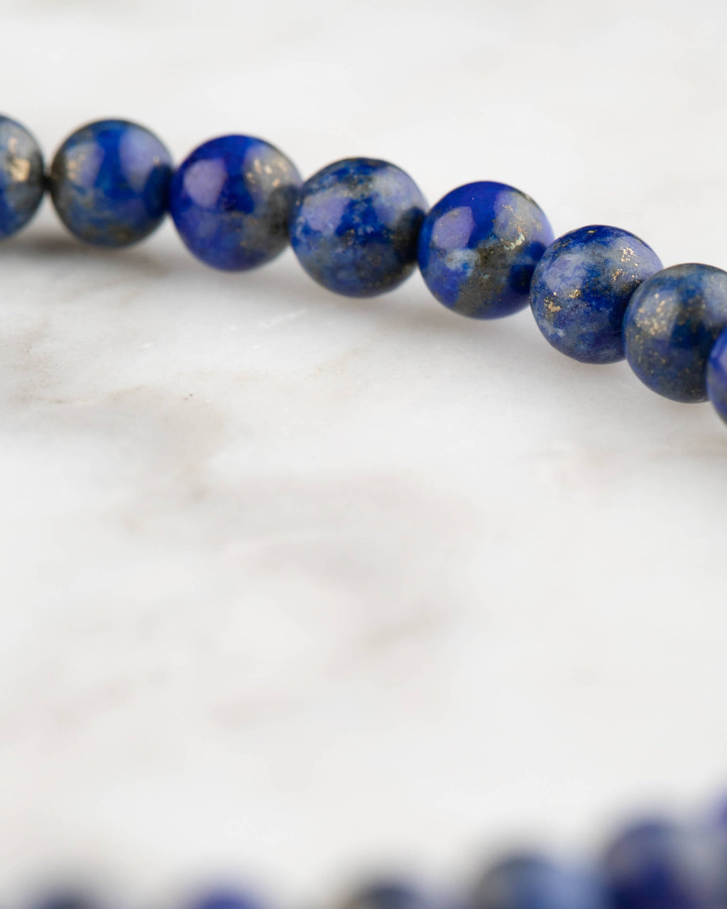 Pulsera de Lapislázuli en ángulo, cuentas azules con degradado de enfoque sobre mármol