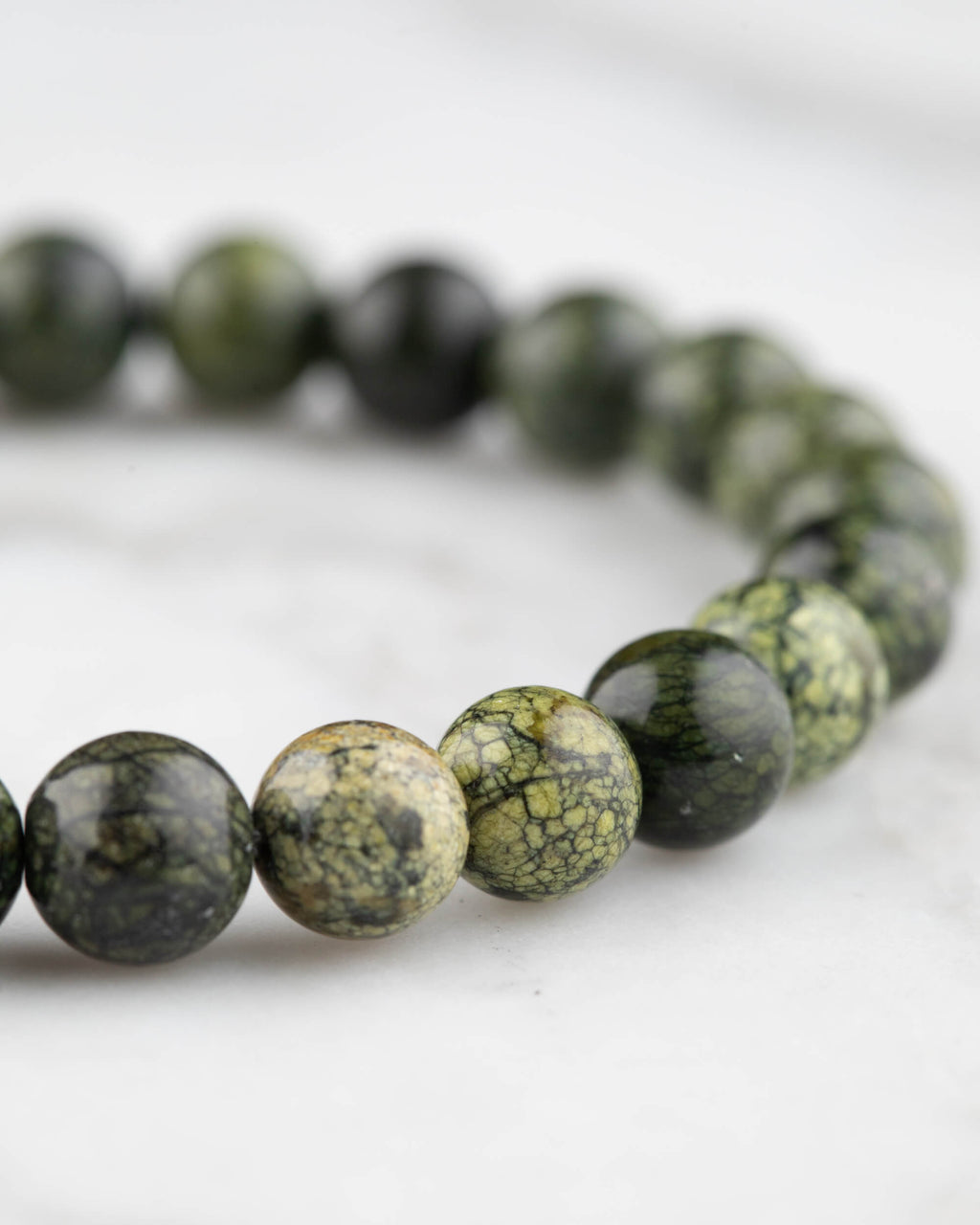 Detalle cercano de la pulsera de Serpentina sobre superficie de mármol claro