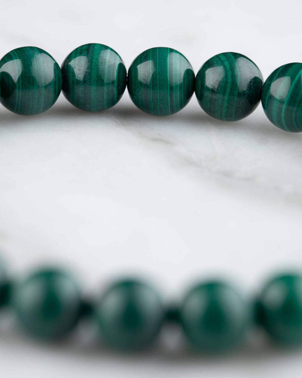 Pulsera de Malaquita en perspectiva curva sobre mármol claro