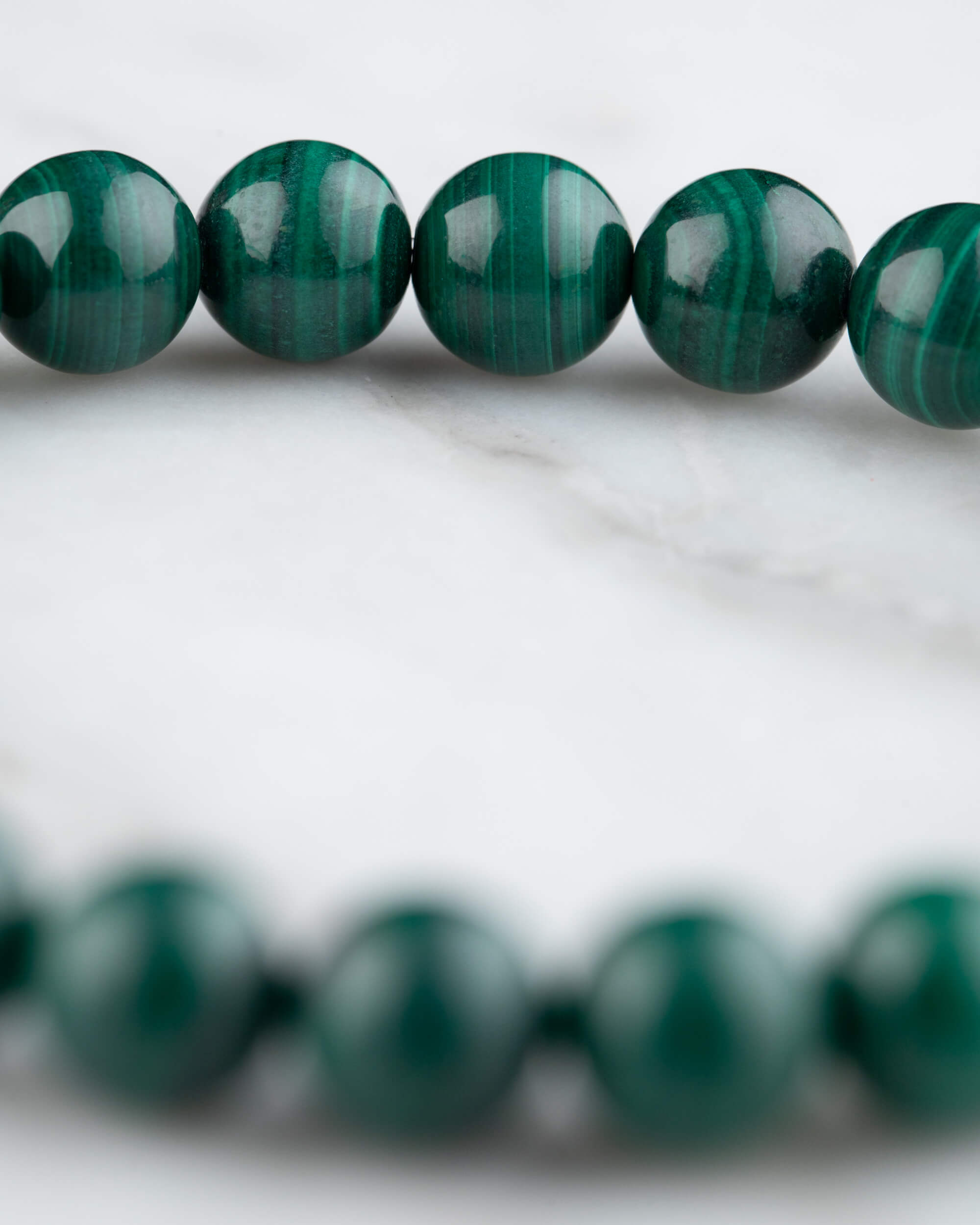 Pulsera de Malaquita en perspectiva curva sobre mármol claro