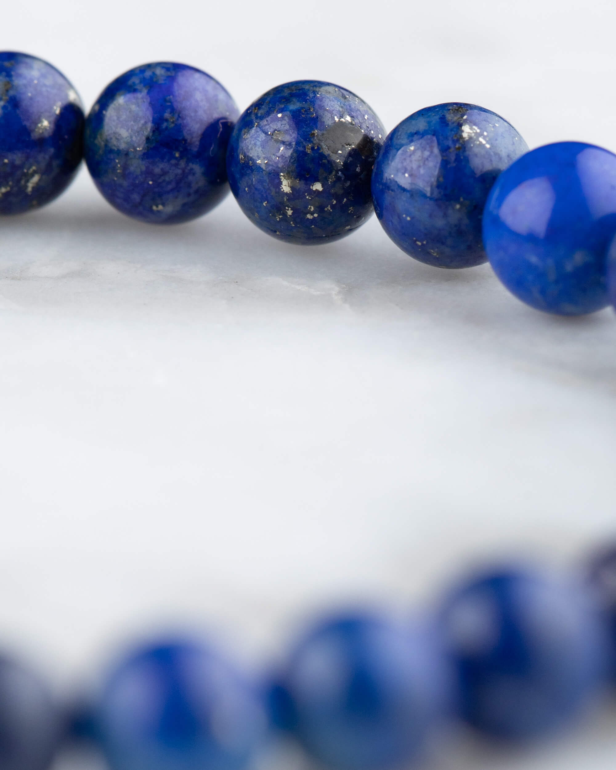 Pulsera de Lapislázuli en perspectiva curva sobre mármol claro