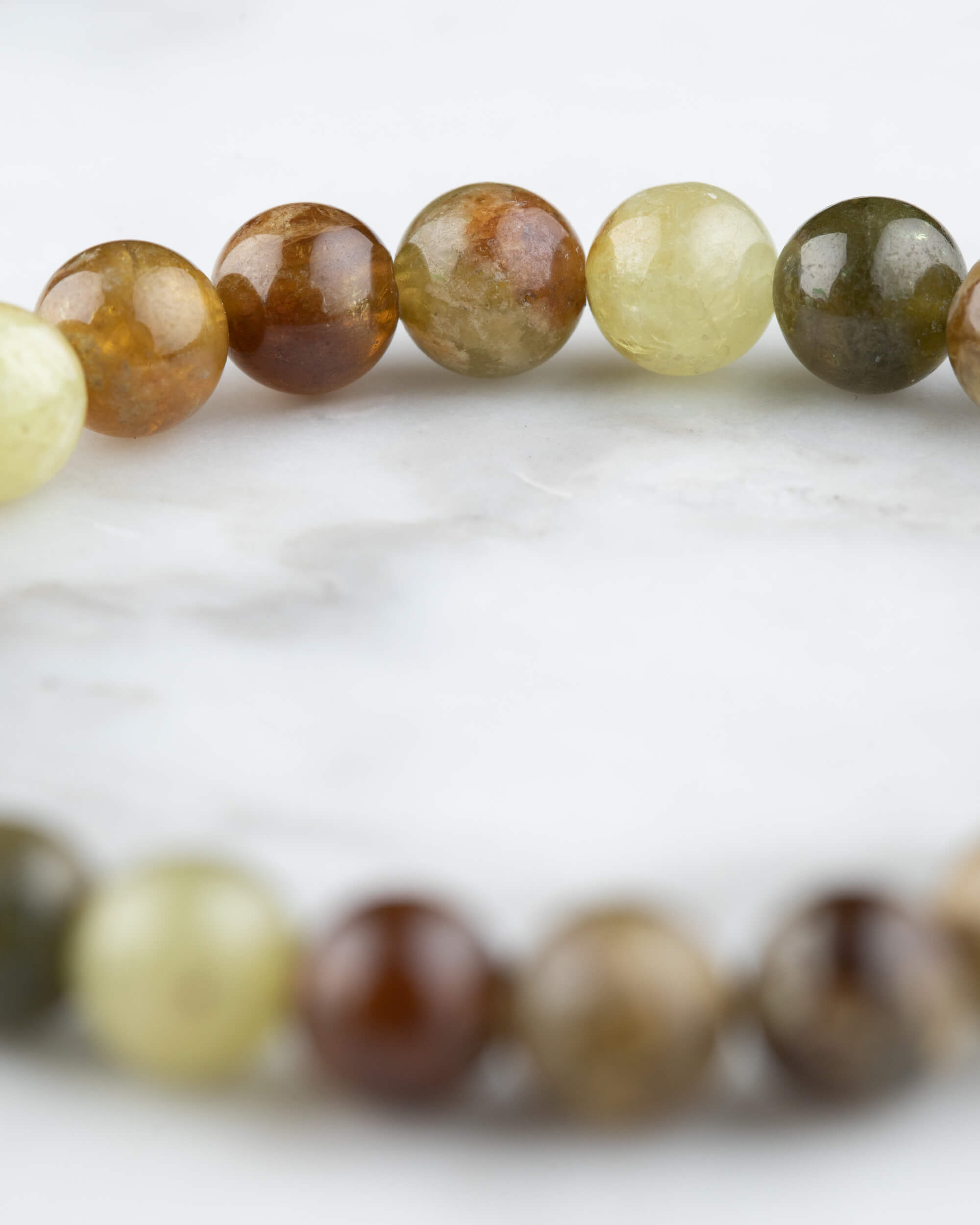 Pulsera de Granate Grosularia en perspectiva curva sobre mármol claro