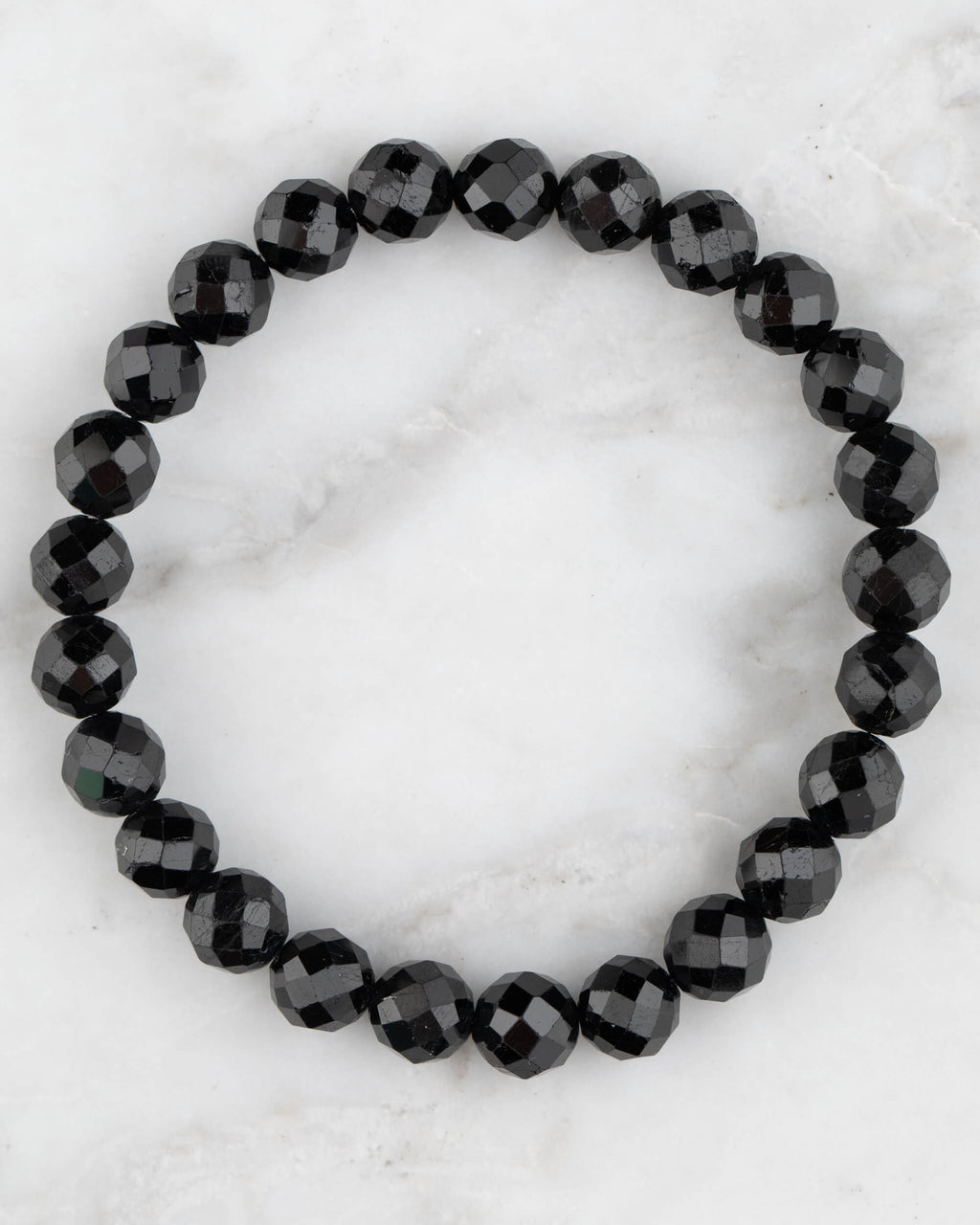 Pulsera de Turmalina Negra facetada de 8 mm, pieza completa en círculo sobre mármol