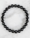 Pulsera de Turmalina Negra facetada de 8 mm, pieza completa en círculo sobre mármol