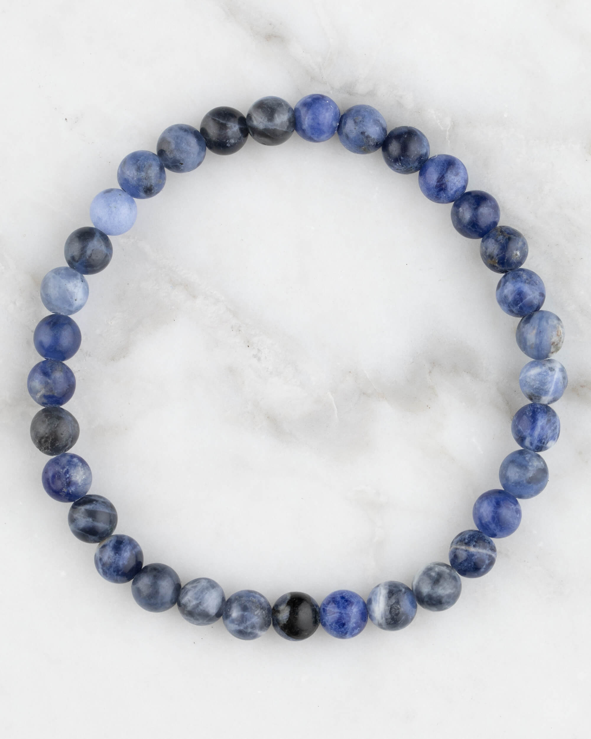 Pulsera de Sodalita de 6 mm, pieza completa en círculo sobre superficie de mármol