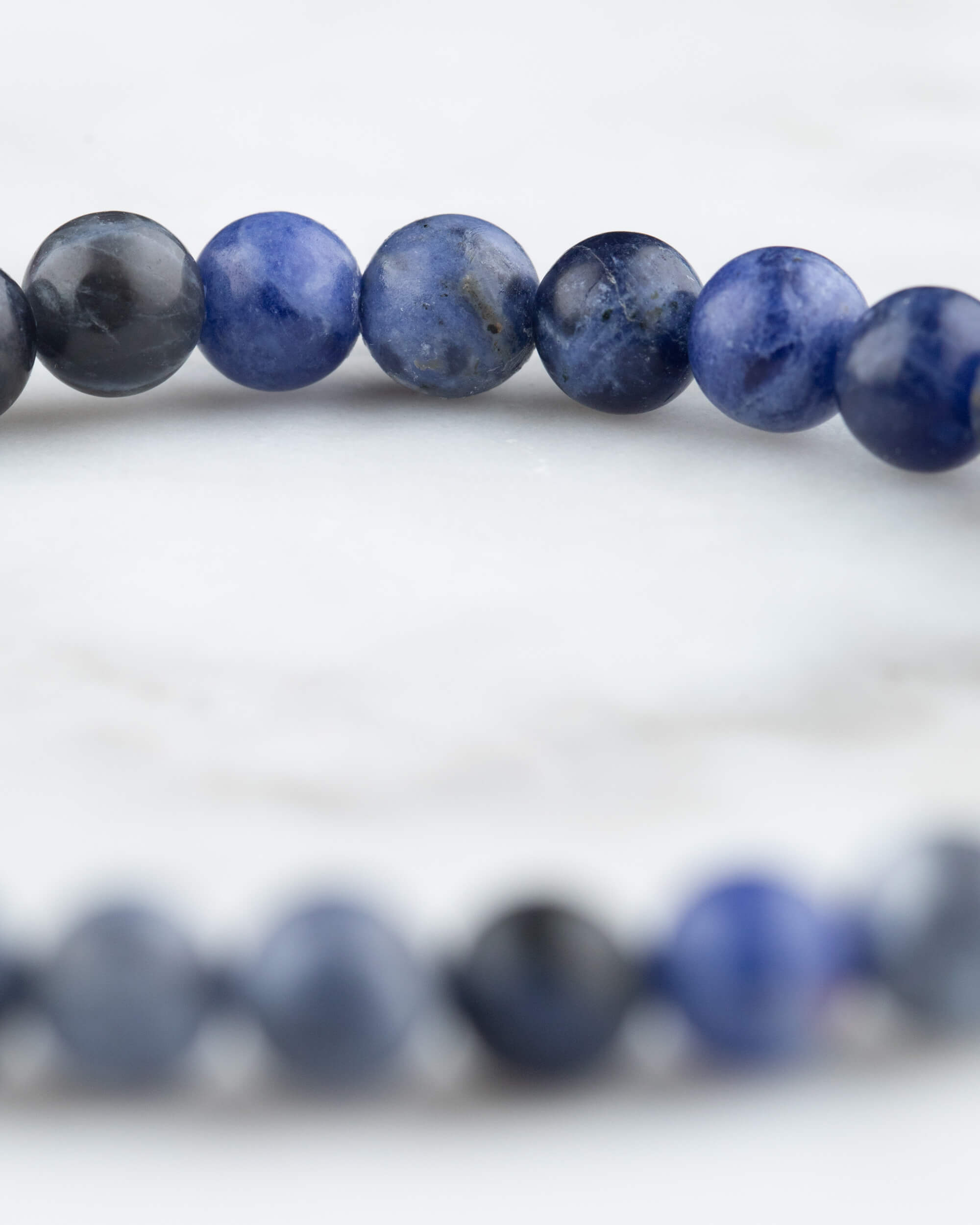 Cuentas de Sodalita en detalle cercano, arco de la pulsera sobre superficie clara